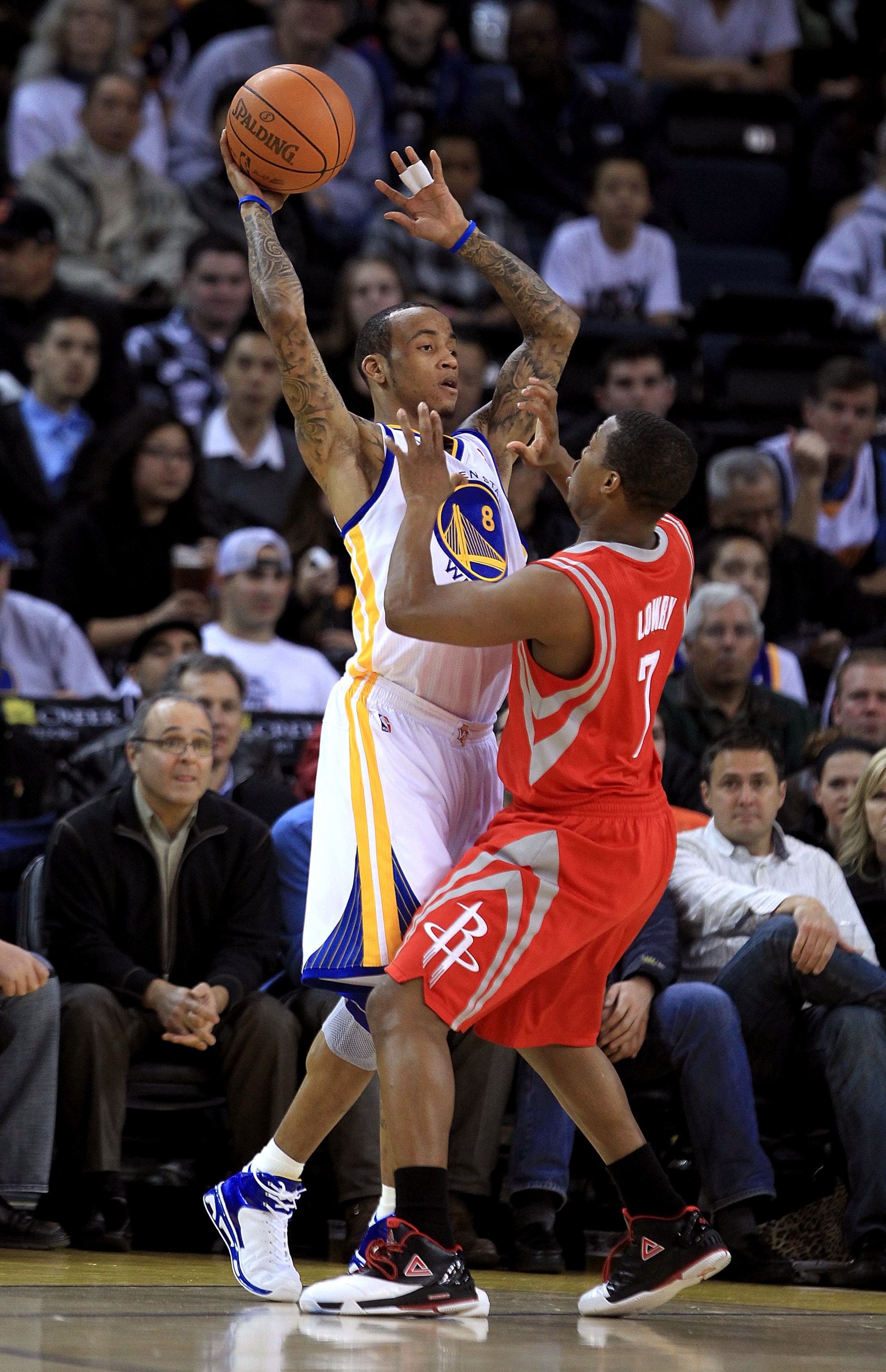OAKLAND, CA - DECEMBER 20:  Monta Ellis #8 of the Golden State Warriors tries to pass around Kyle Lowry #7 of the Houston Rockets at Oracle Arena on December 20, 2010 in Oakland, California. NOTE TO USER: User expressly acknowledges and agrees that, by do