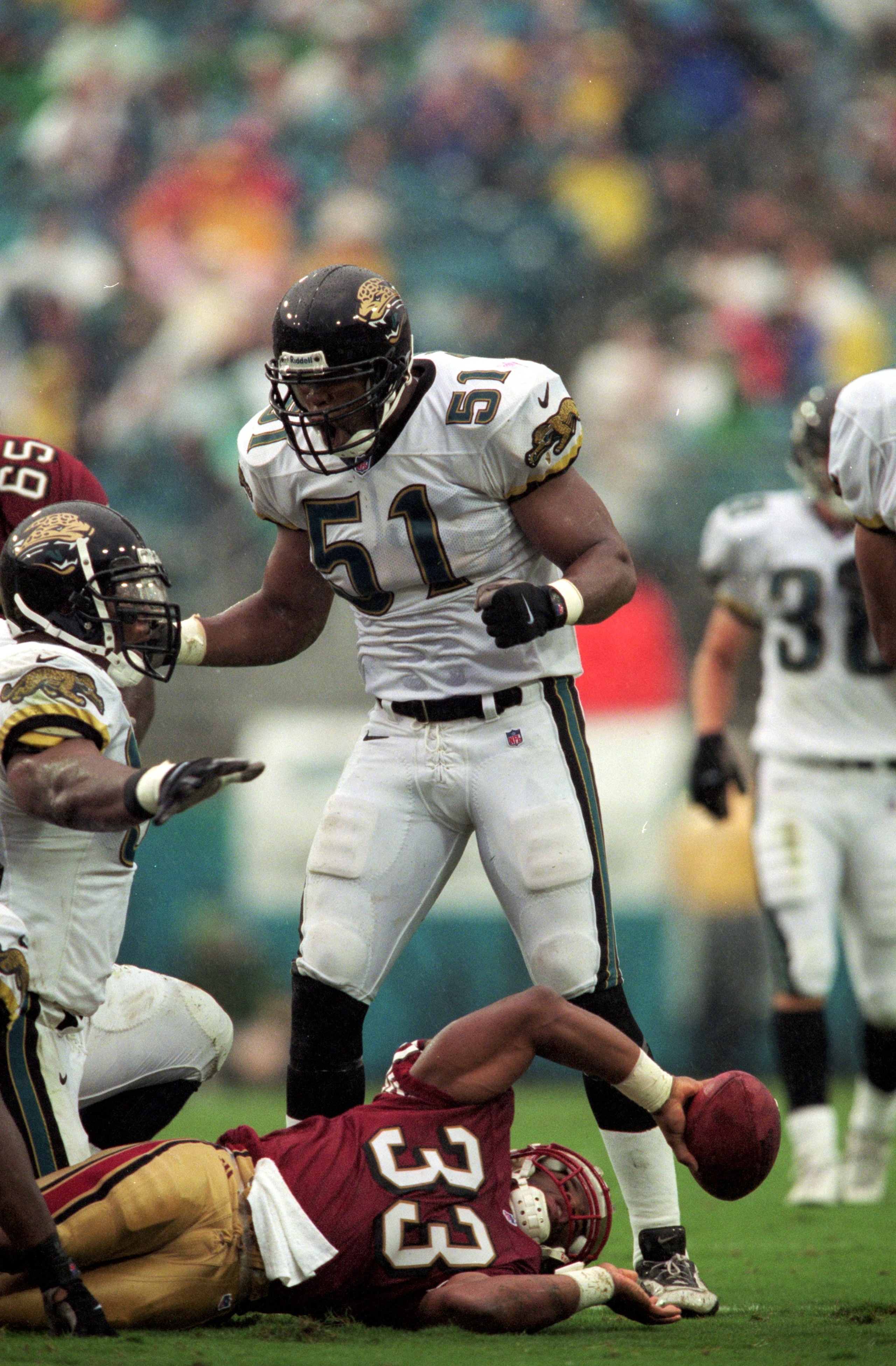 12 Sep 1999: Kevin Hardy #51 of the Jacksonville Jaguars helps his teammate up after they tackle Lawrence Phillips #33 of the San Francisco 49ers during the game at the Alltell Stadium in Jacksonville, Florida. The Jaguars defeated the 49ers 41-3. Mandat 12 Sep 1999: Kevin Hardy #51 of the Jacksonville Jaguars helps his teammate up after they tackle Lawrence Phillips #33 of the San Francisco 49ers during the game at the Alltell Stadium in Jacksonville, Florida. The Jaguars defeated the 49ers 41-3. Mandat