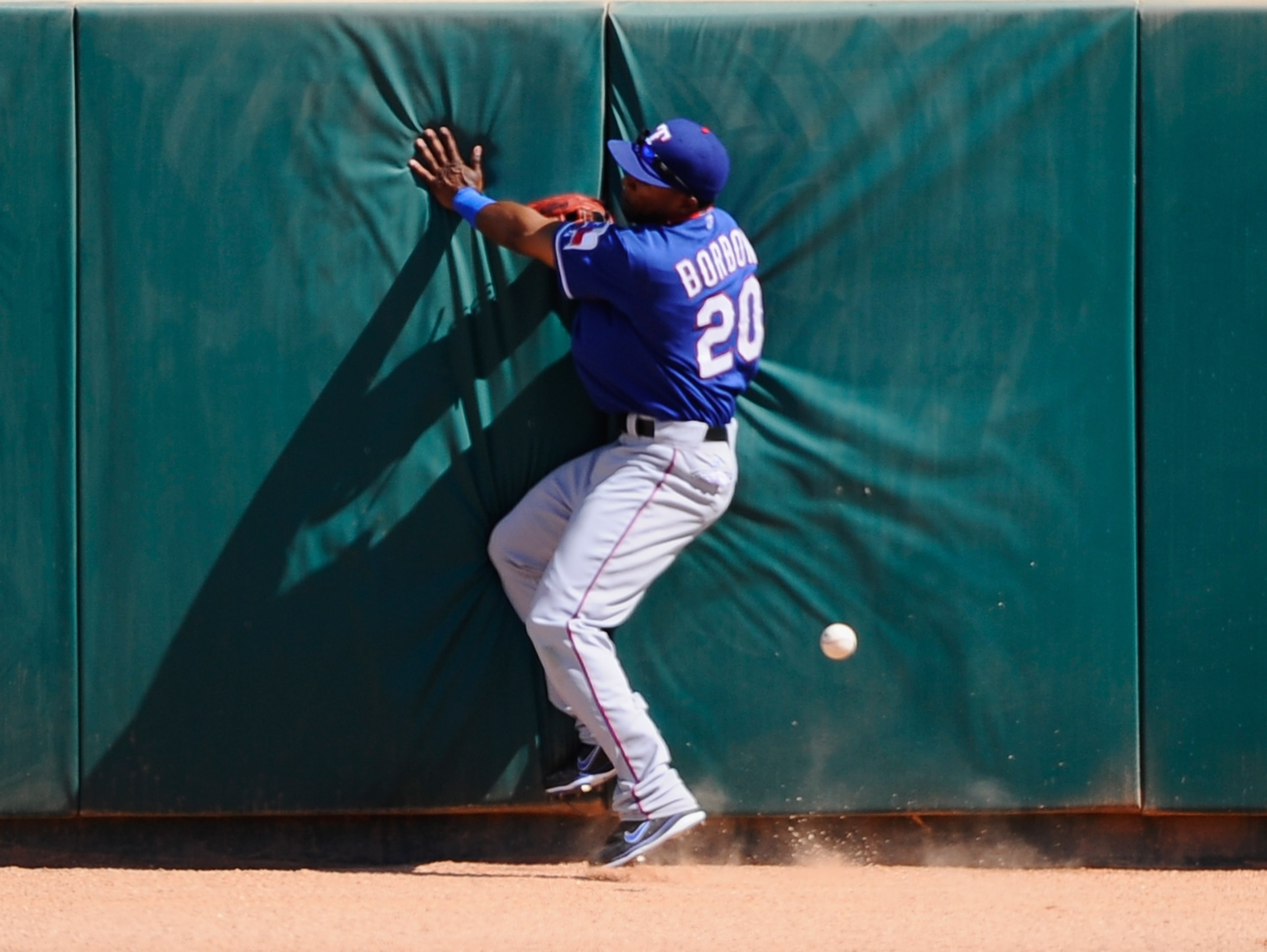 GLENDALE, AZ - MARCH 15: Julio Borbon #20 of the Texas Rangers crashes against the center field wall as he chases a two-run triple by Juan Uribe #5 of the Los Angeles Dodgers that scored Ivan DeJesus #65 and Andre Ethier #16 during the thrid inning of th GLENDALE, AZ - MARCH 15: Julio Borbon #20 of the Texas Rangers crashes against the center field wall as he chases a two-run triple by Juan Uribe #5 of the Los Angeles Dodgers that scored Ivan DeJesus #65 and Andre Ethier #16 during the thrid inning of th
