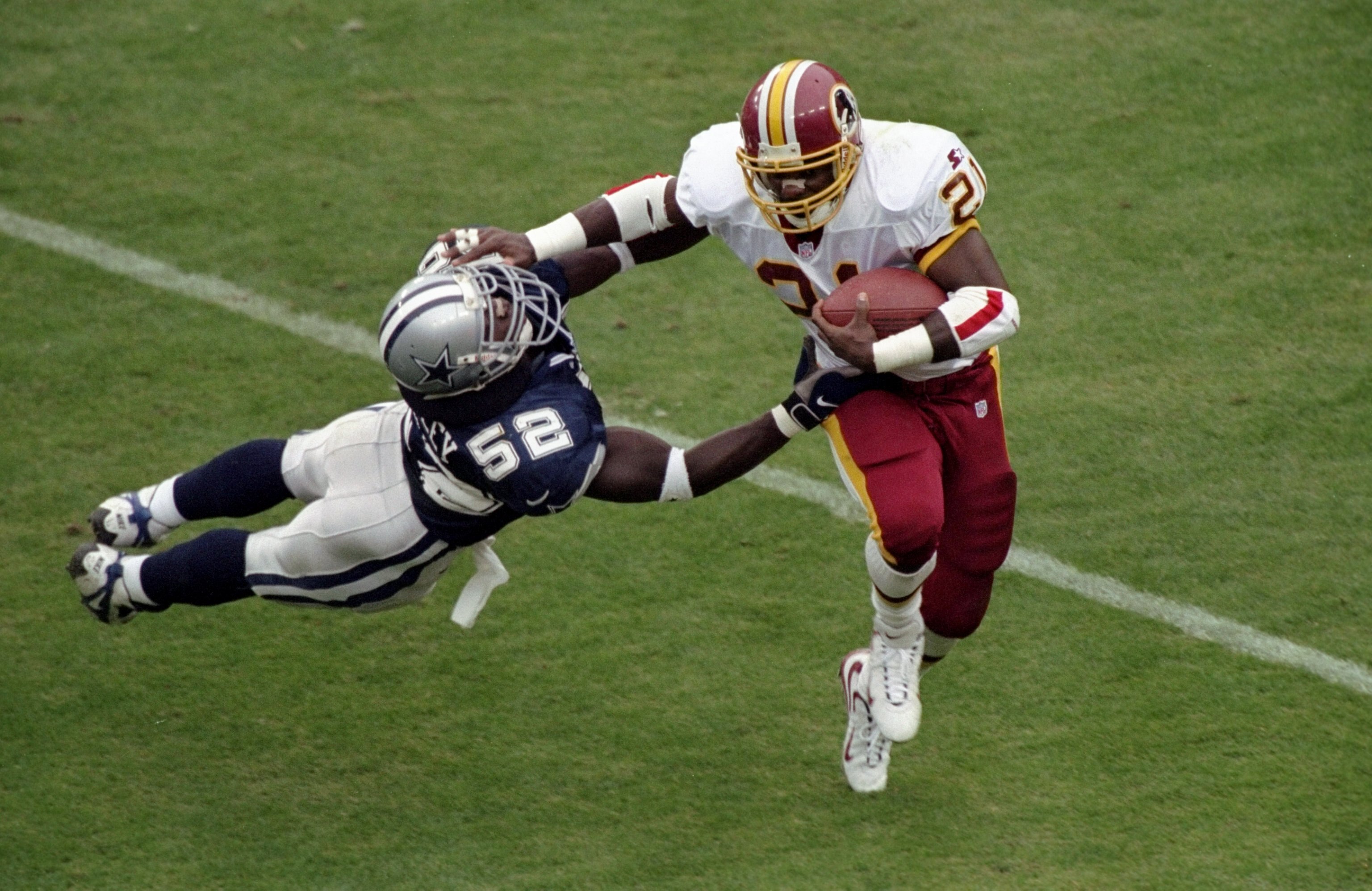 4 Oct 1998:  Runningback Terry Allen #21 of the Washington Redskins runs with the ball as Dexter Coakley #52 of the Dallas Cowboys dives to tackle Allen during a game at the Jack Kent Cooke Stadium in Landover, Maryland. The Cowboys defeated the Redskins