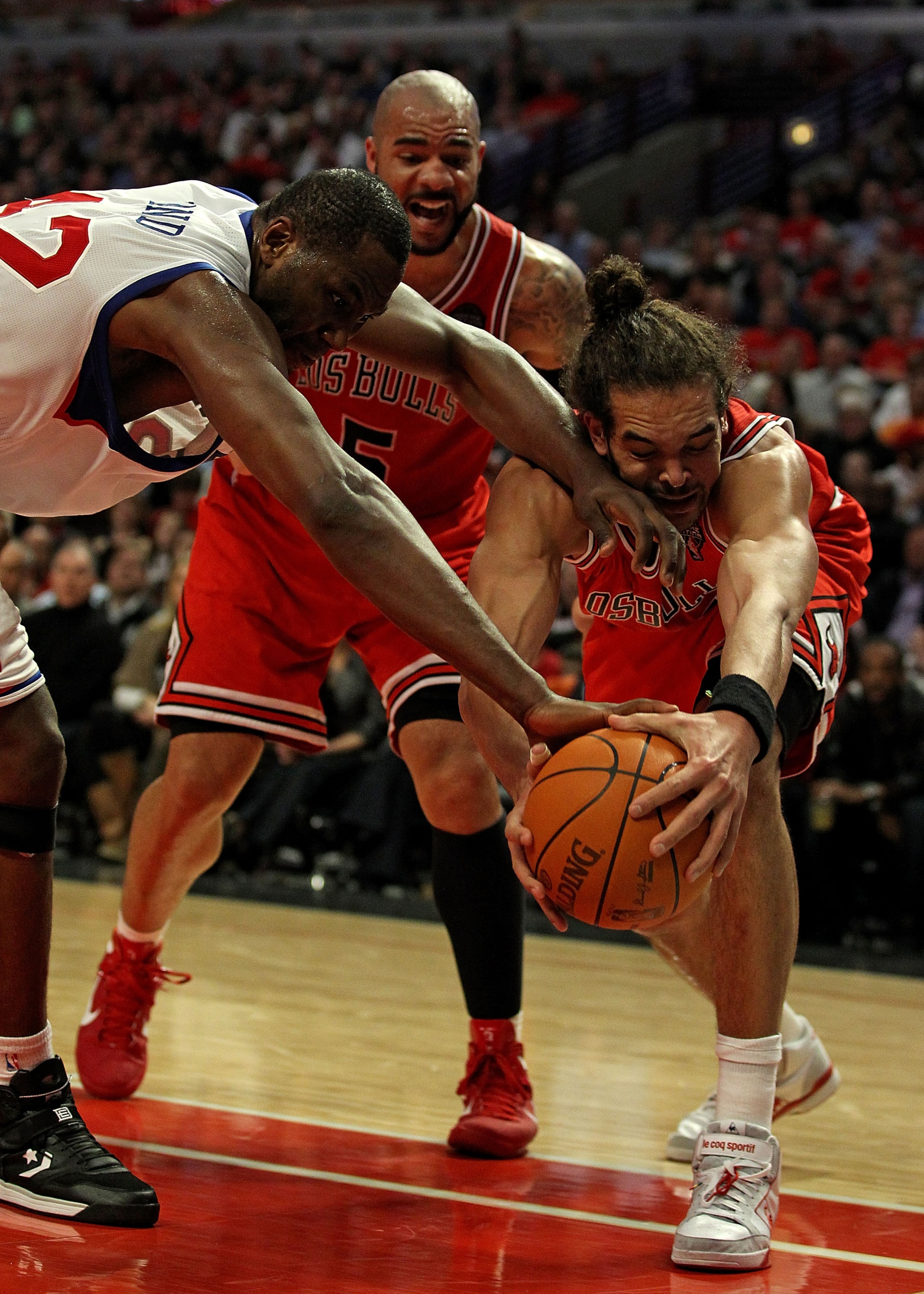 CHICAGO, IL - MARCH 28: Joakim Noah #13 of the Chicago Bulls battles for the ball with Elton Brand #42 of the Philadelphia 76ers in front of Carlos Boozer #5 at the United Center on March 28, 2011 in Chicago, Illinois. The 76ers defeated the Bulls 97-85.