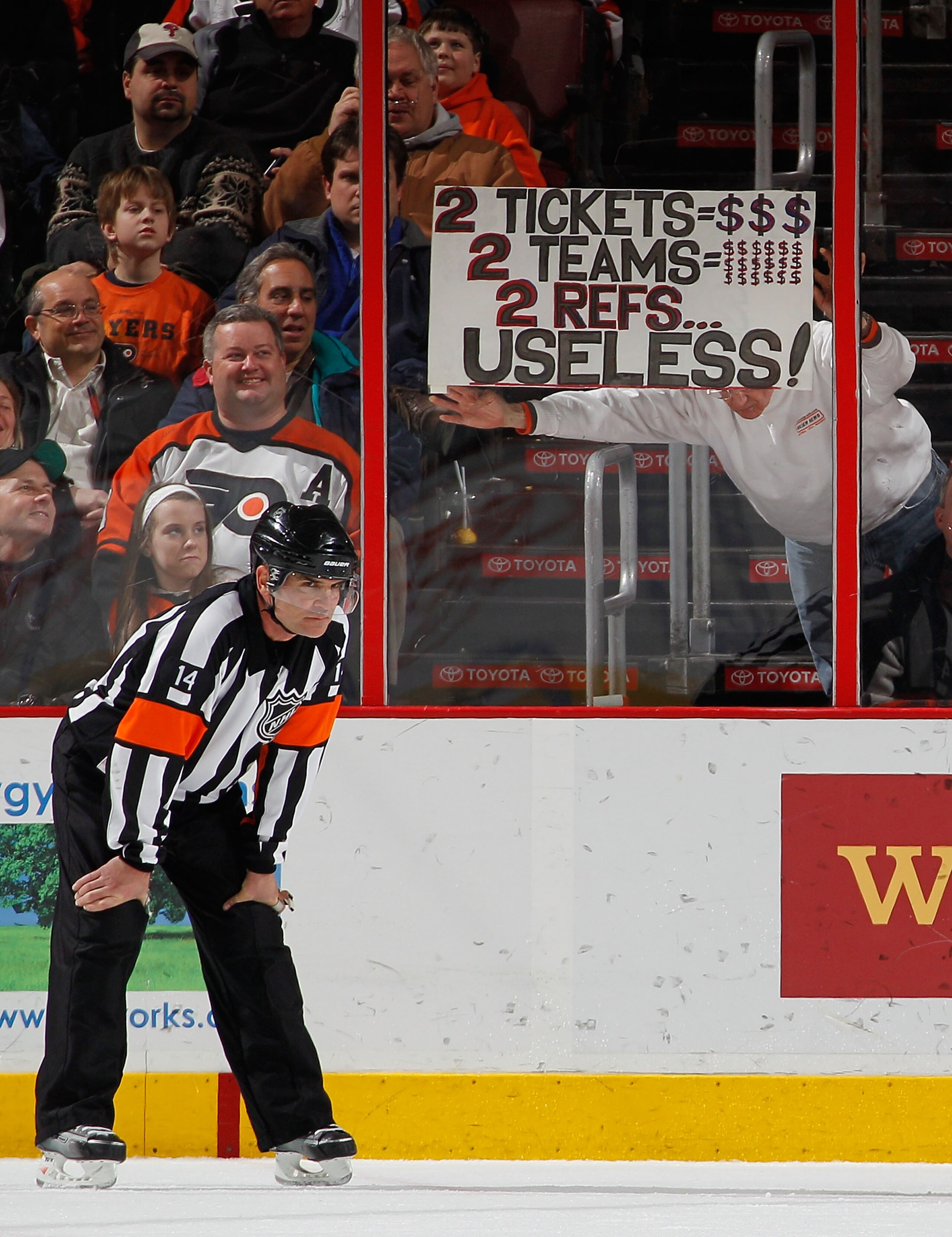PHILADELPHIA, PA - FEBRUARY 03:  Fans hold up a sign behind referee Dennis LaRue #14 as he waits for a faceoff during an NHL hockey game between the Nashville Predators and the Philadelphia Flyers at the Wells Fargo Center on February 3, 2011 in Philadelp