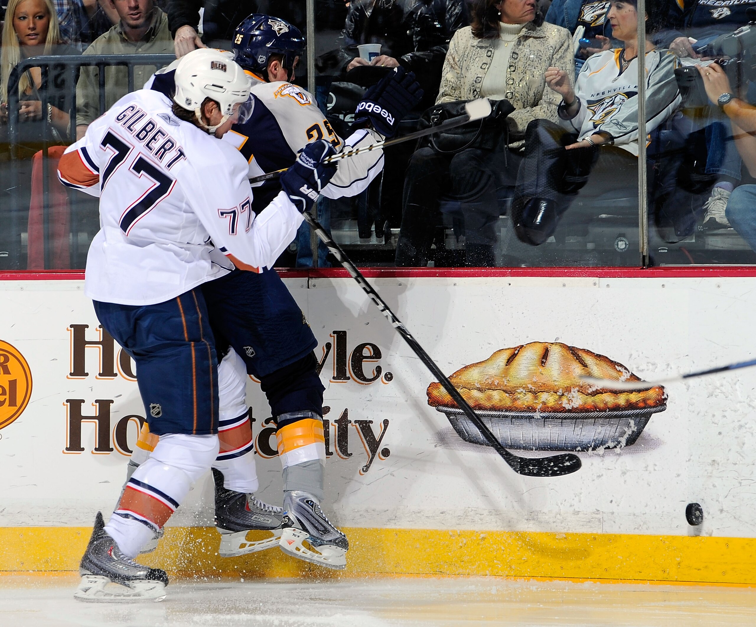 NASHVILLE, TN - MARCH 22:  Tom Gilbert #77 of the Edmonton Oilers checks Jered Smithson #25 of the Nashville Predators on March 22, 2011 at the Bridgestone Arena in Nashville, Tennessee.  (Photo by Frederick Breedon/Getty Images)