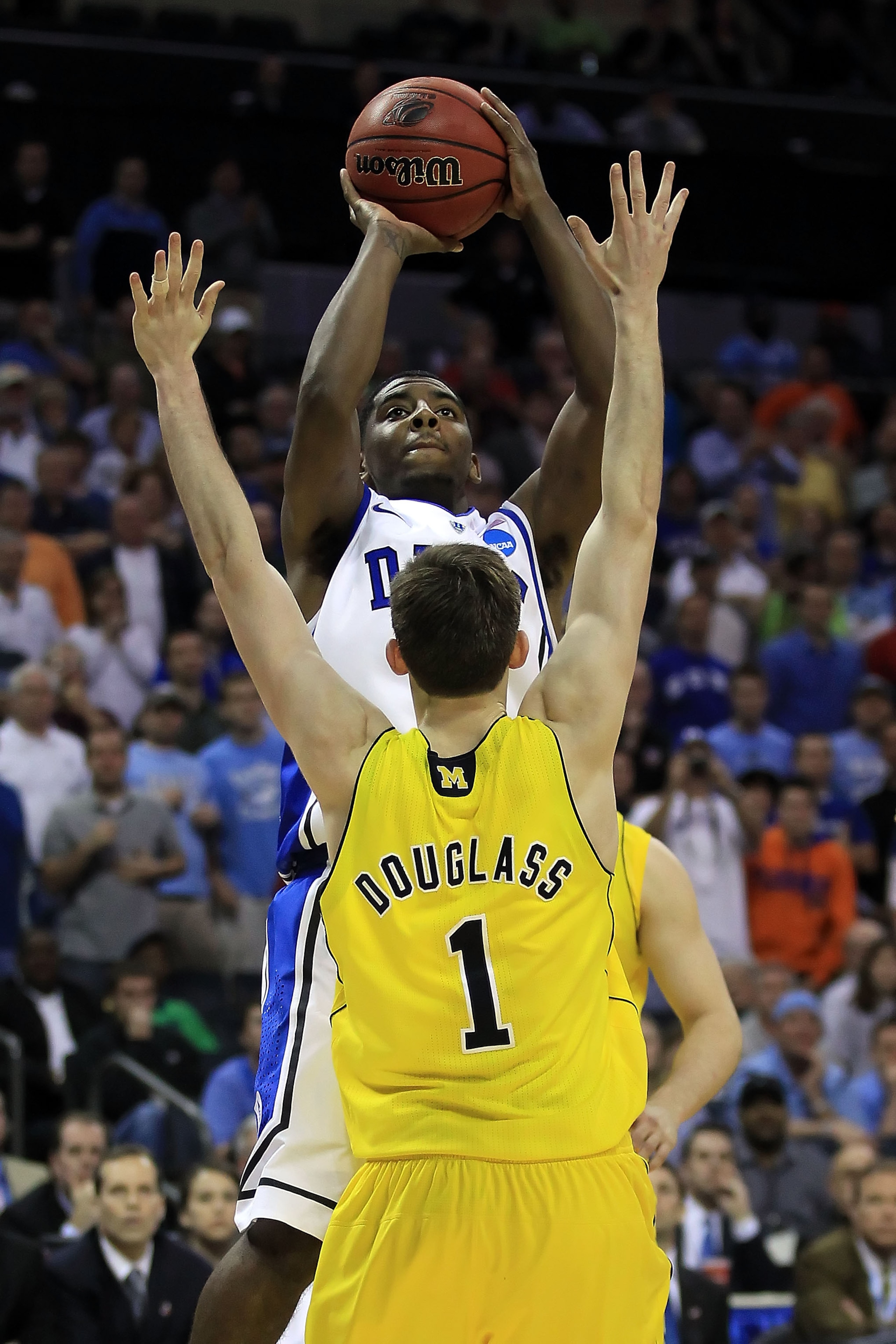 CHARLOTTE, NC - MARCH 20:  Kyrie Irving #1 of the Duke Blue Devils makes the eventual game-winning basket late in the second half while shooting over Stu Douglass #1 of the Michigan Wolverines during the third round of the 2011 NCAA men's basketball tourn