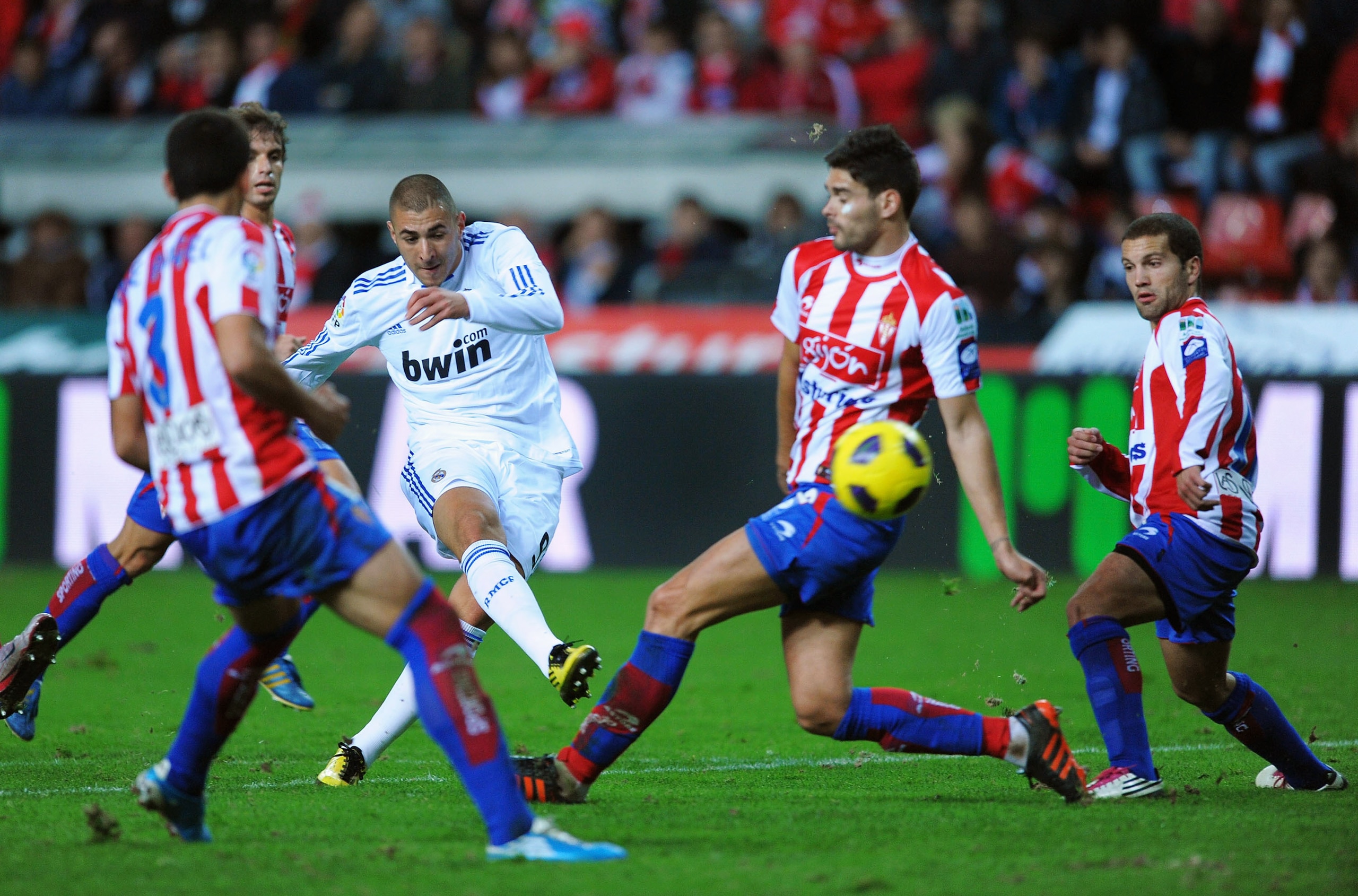 GIJON, SPAIN - NOVEMBER 14: Karim Benzema of Real Madrid shoots through he Sporting Gijon defense during the La Liga match between Sporting Gijon and Real Madrid at El Molinon Stadium on November 14, 2010 in Gijon, Spain.  (Photo by Denis Doyle/Getty Imag