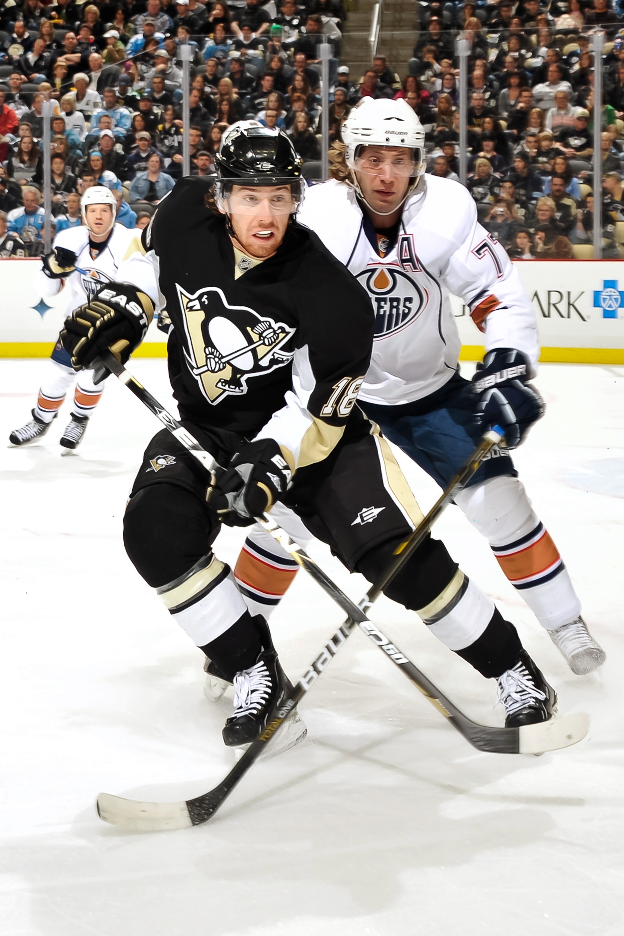 PITTSBURGH, PA - MARCH 13:  James Neal #18 of the Pittsburgh Penguins and Tom Gilbert #77 of the Edmonton Oilers skate after a loose puck on March 13, 2011 at CONSOL Energy Center in Pittsburgh, Pennsylvania.  (Photo by Jamie Sabau/Getty Images)