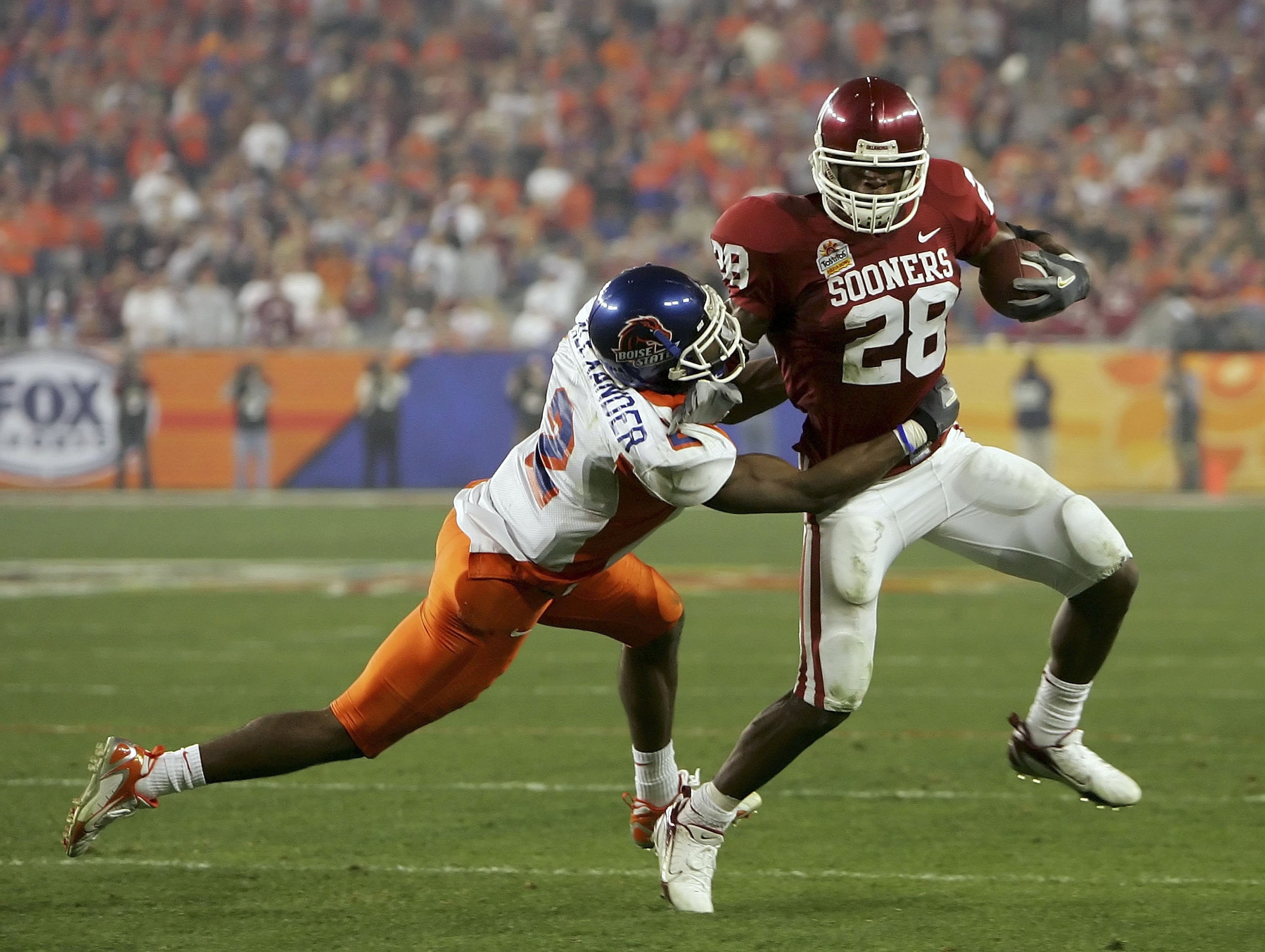 GLENDALE, AZ - JANUARY 1:  Adrian Peterson #28 of the Oklahoma Sooners looks to break a safety Gerald Alexander #2 of the Boise State Broncos tackle in the first half at the Tostito's Fiesta Bowl against the Boise State Broncos at University of Phoenix St