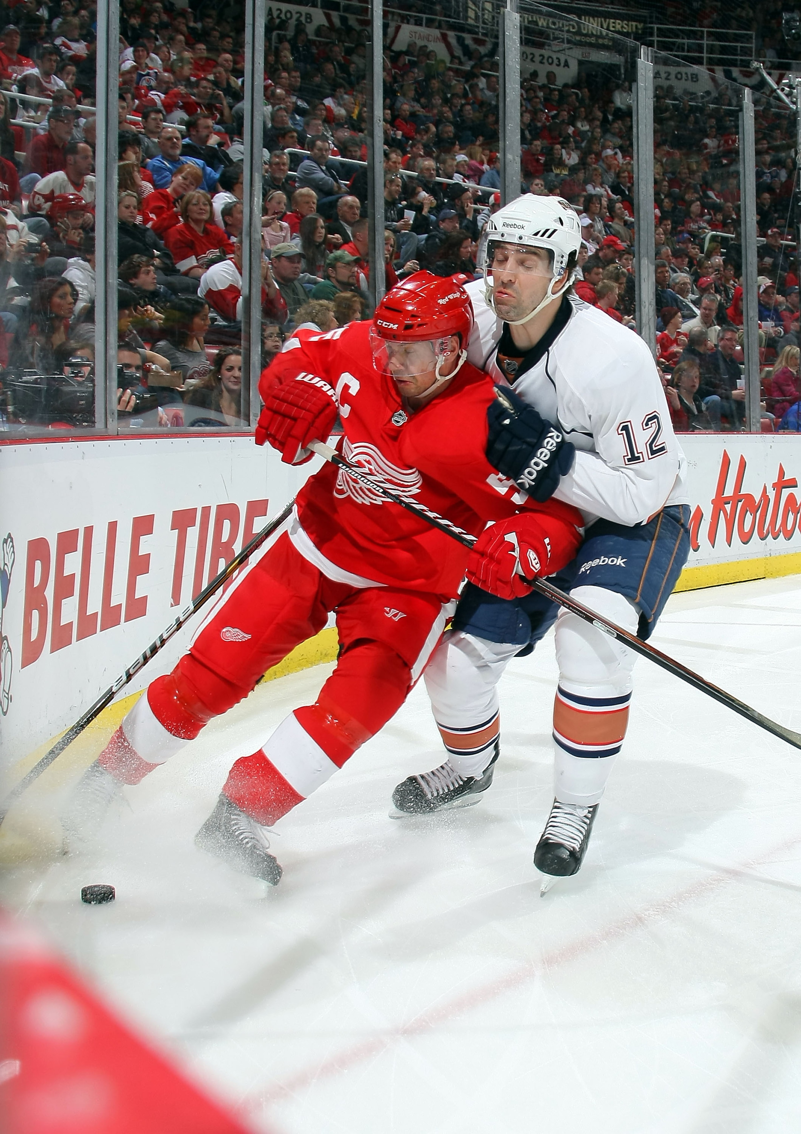 DETROIT, MI - MARCH 11:  Alexandre Giroux #12 of the Edmonton Oilers battles for the puck with Nicklas Lidstrom #5 of the Detroit Red Wings during their NHL game at Joe Louis Arena on March 11, 2011 in Detroit, Michigan.  (Photo by Dave Sandford/Getty Ima