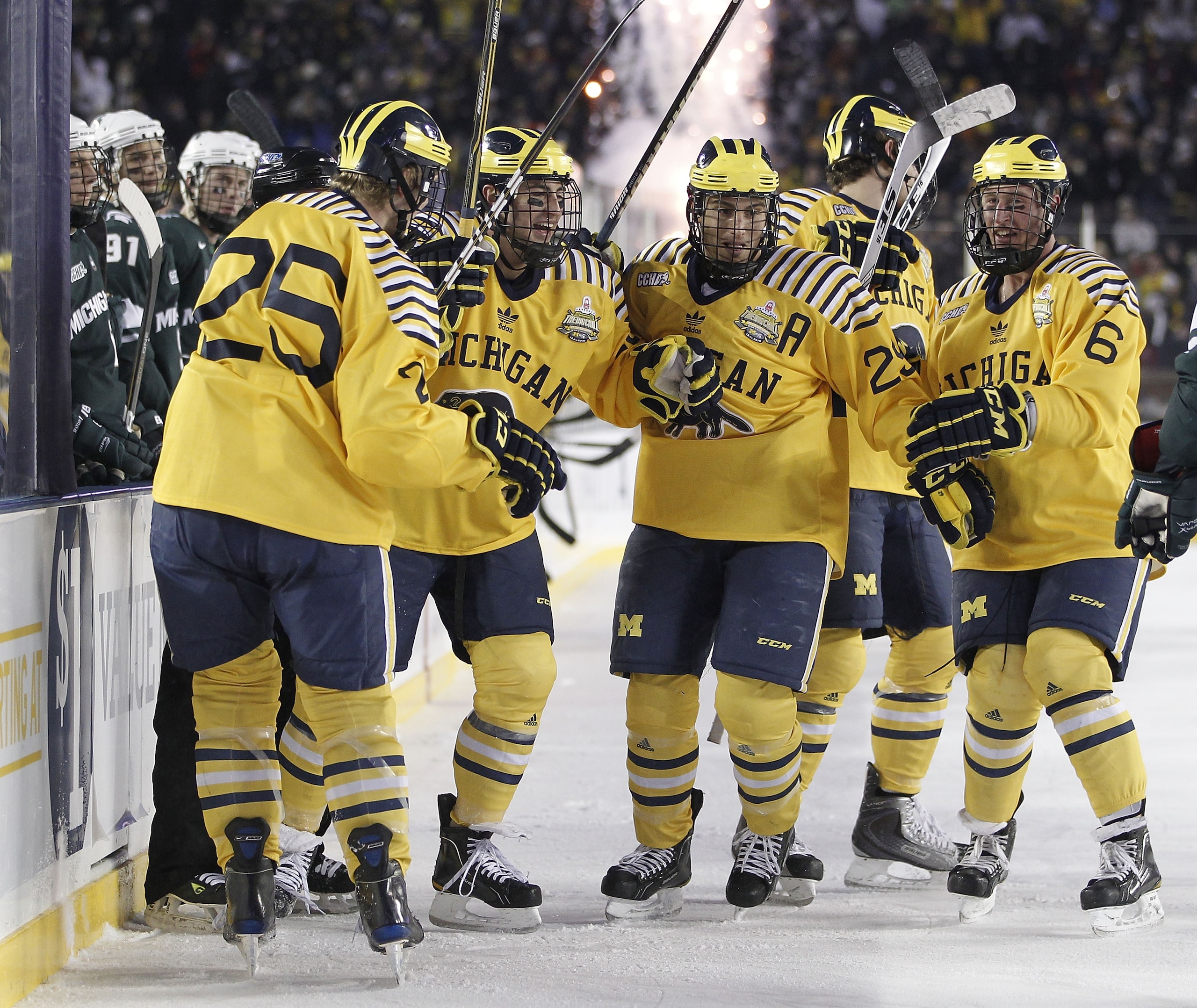 ANN ARBOR, MI - DECEMBER 11:  David Wohlberg #25 of the Michigan Wolverines celebrates a third period goal with and Lee Moffie #13, Louie Caporusso #29 and Brandon Burlon #6 while playing the Michigan State Spartans at Michigan Stadium on December 11, 201