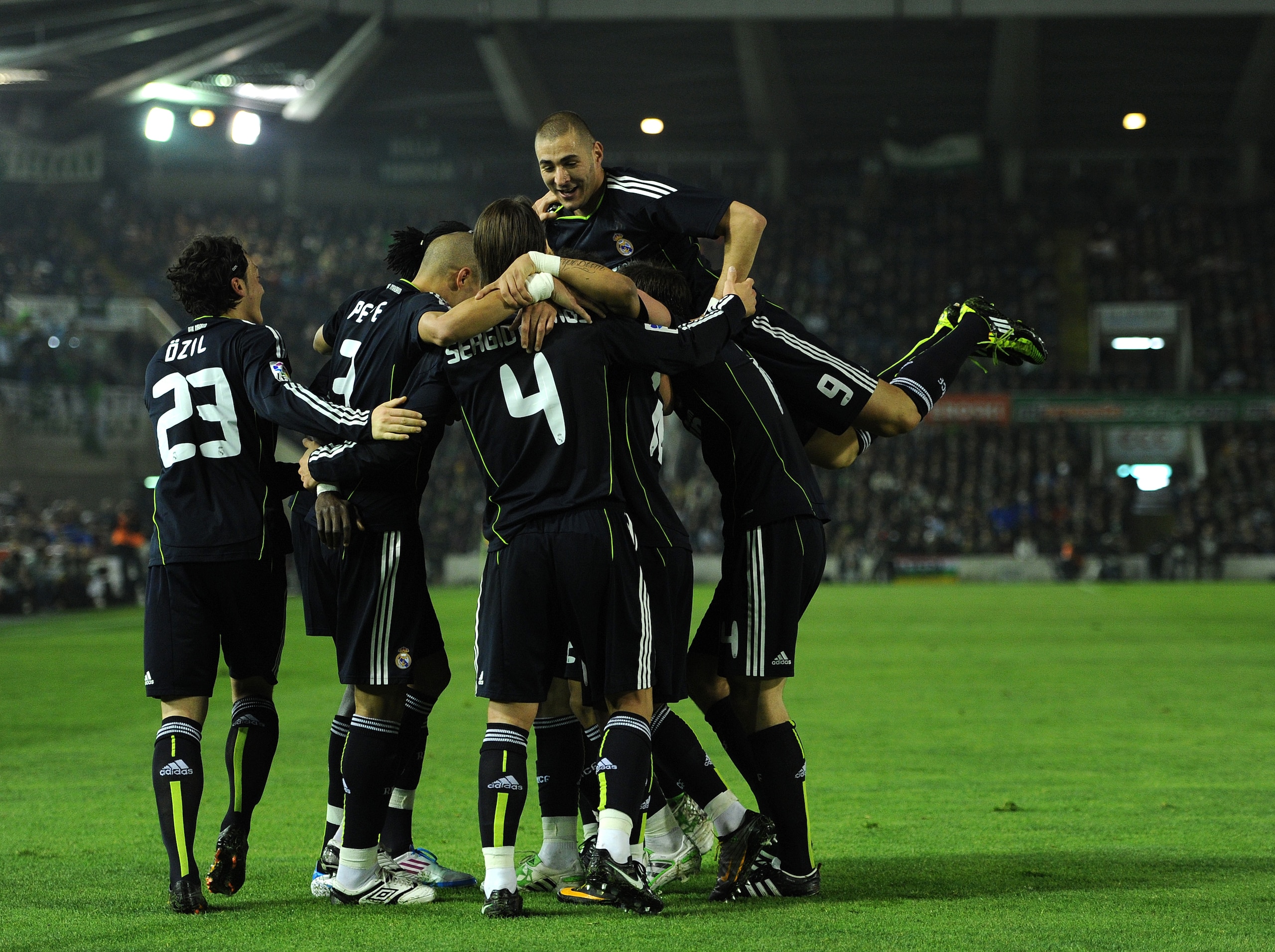 SANTANDER, SPAIN - MARCH 06:  Karim Benzema (R) of Real Madrid jumps on top of his teammates as they celebrate Emanuel Abadayour's opening goal during the la Liga match between Racing Santander and Real Madrid at El Sardinero stadium on March 6, 2011 in S