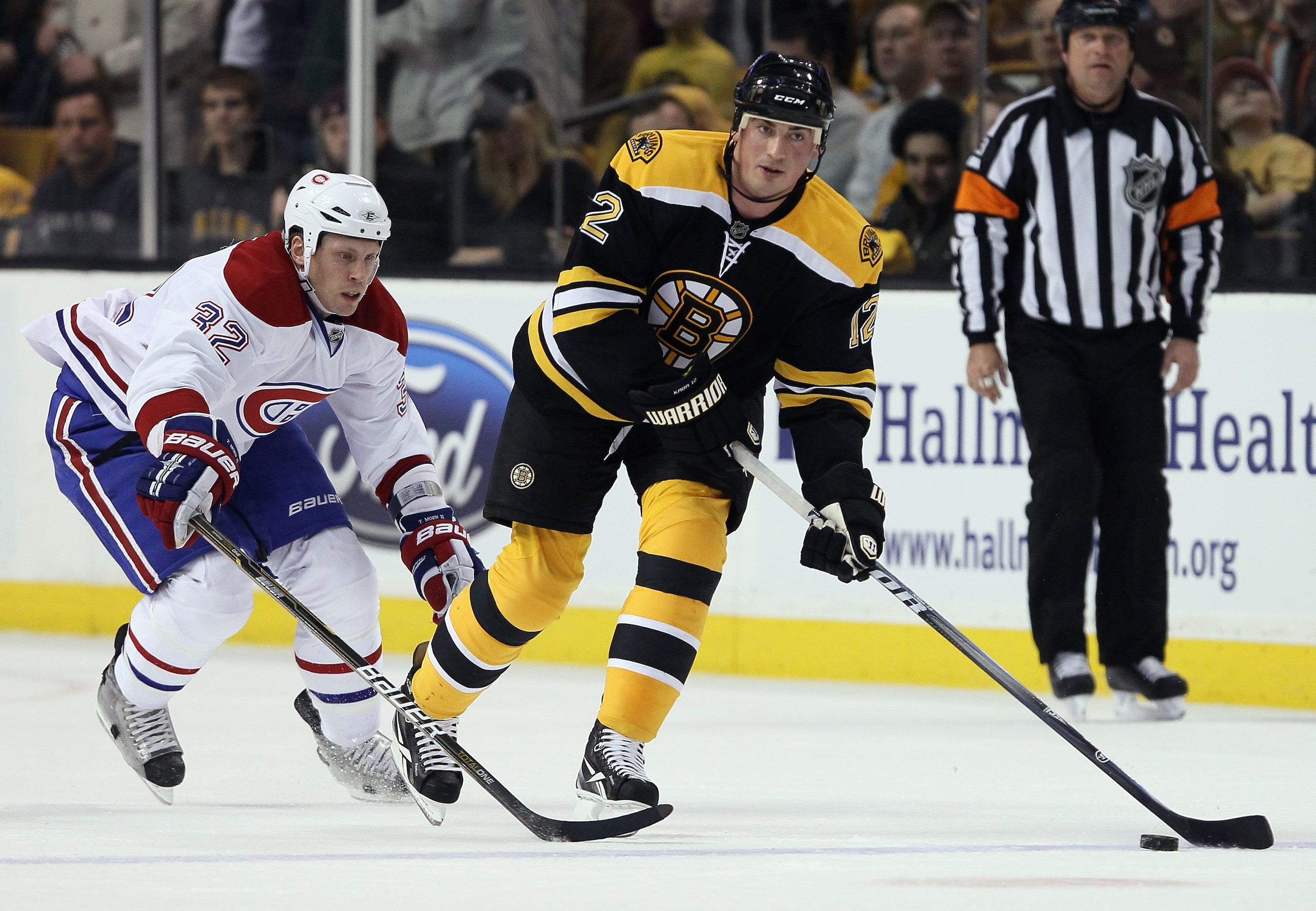 BOSTON, MA - MARCH 24:  Tomas Kaberle #12 of the Boston Bruins takes the puck as Travis Moen #32 of the Montreal Canadiens defends on March 24, 2011 at the TD Garden in Boston, Massachusetts.  (Photo by Elsa/Getty Images)