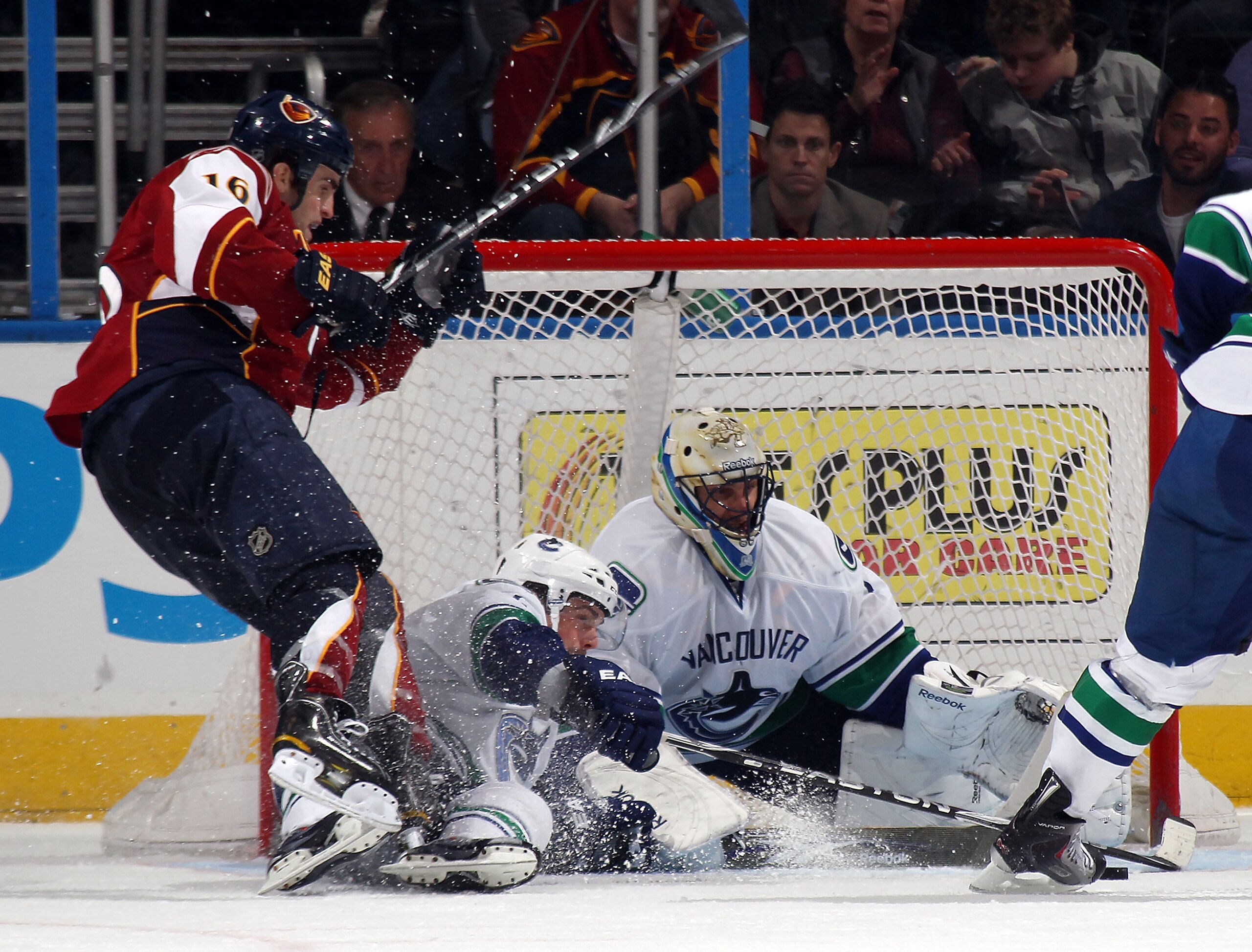 ATLANTA, GA - MARCH 25: Roberto Luongo #1 of the Vancouver Canucks makes the kick save in the third period as Andrew Ladd #16 of the Atlanta Thrashers is tripped up in front at the Philips Arena on March 25, 2011 in Atlanta, Georgia. The Canucks defeated