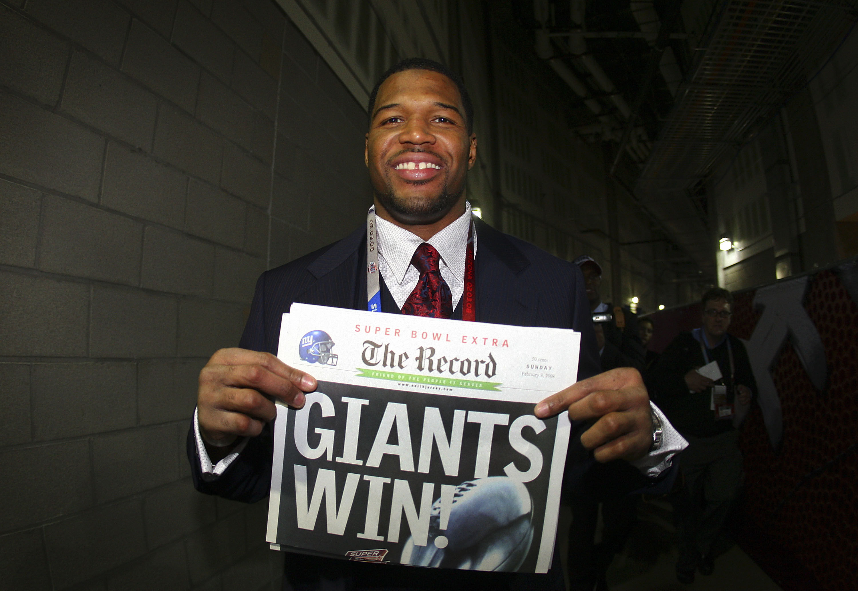 GLENDALE, AZ - FEBRUARY 03: Defensive end Michael Strahan #92 of the New York Giants holds a newspaper with the headline 'GIANTS WIN!' after the Giants defeated the New England Patriots 17-14 during Super Bowl XLII on February 3, 2008 at the University o