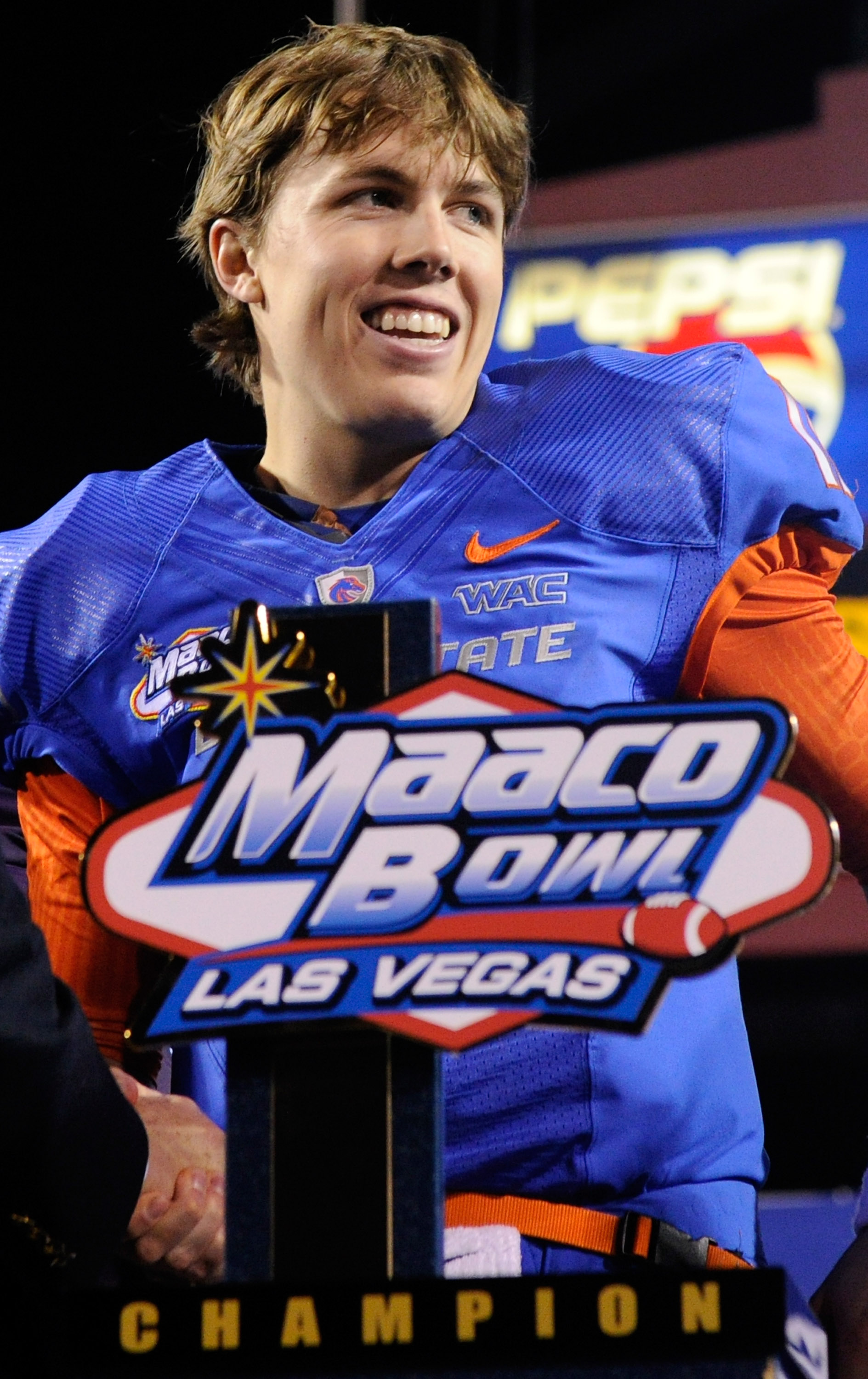 LAS VEGAS, NV - DECEMBER 22:  Quarterback Kellen Moore #11 of the Boise State Broncos smiles while standing behind a trophy as he celebrates the team's 26-3 victory over the Utah Utes in the MAACO Bowl Las Vegas at Sam Boyd Stadium December 22, 2010 in La