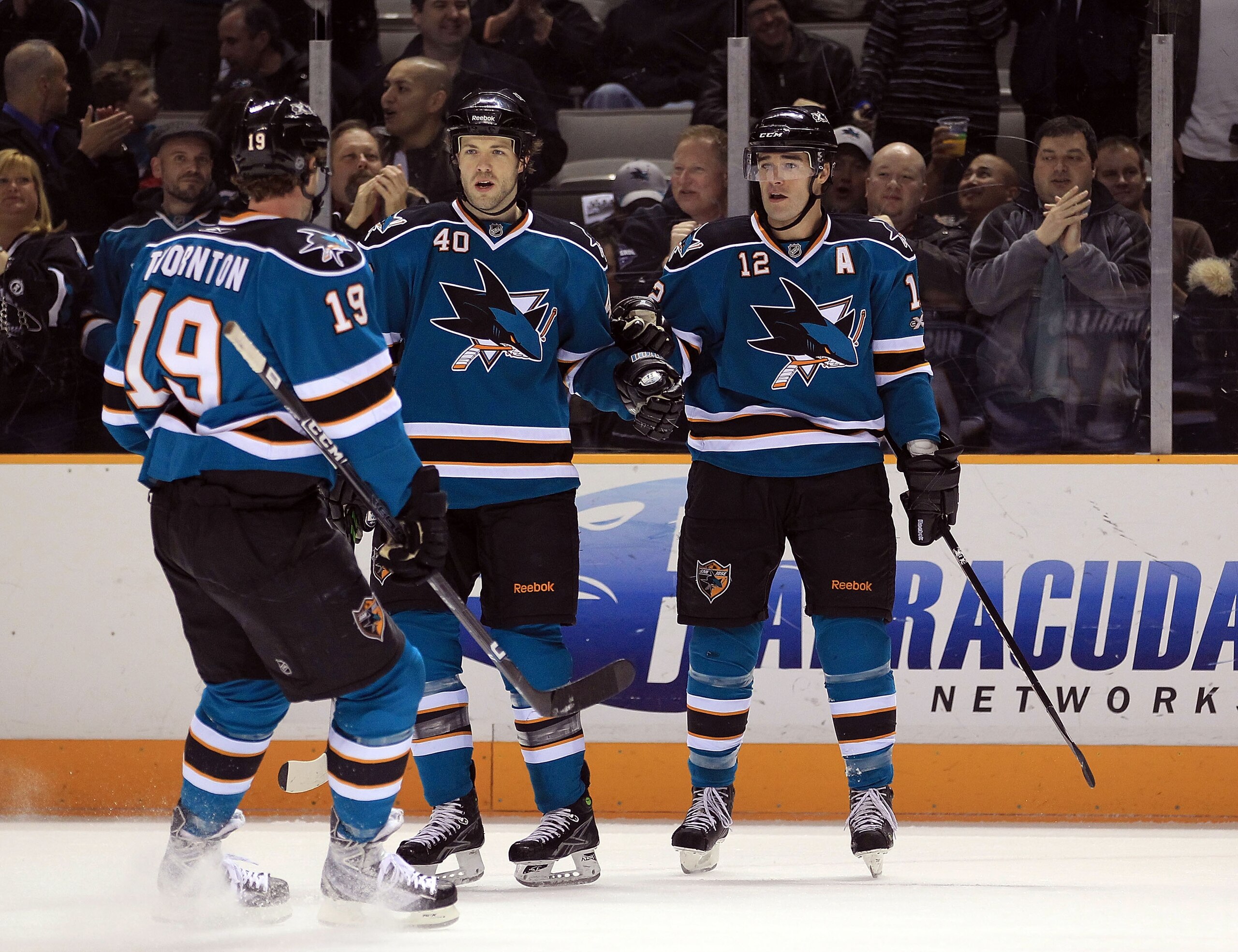 SAN JOSE, CA - JANUARY 11:  Patrick Marleau #12 is congratulated by Kent Huskins #40 and Joe Thornton #19 of the San Jose Sharks after Marleau scored a goal against the Toronto Maple Leafs at HP Pavilion on January 11, 2011 in San Jose, California.  (Phot