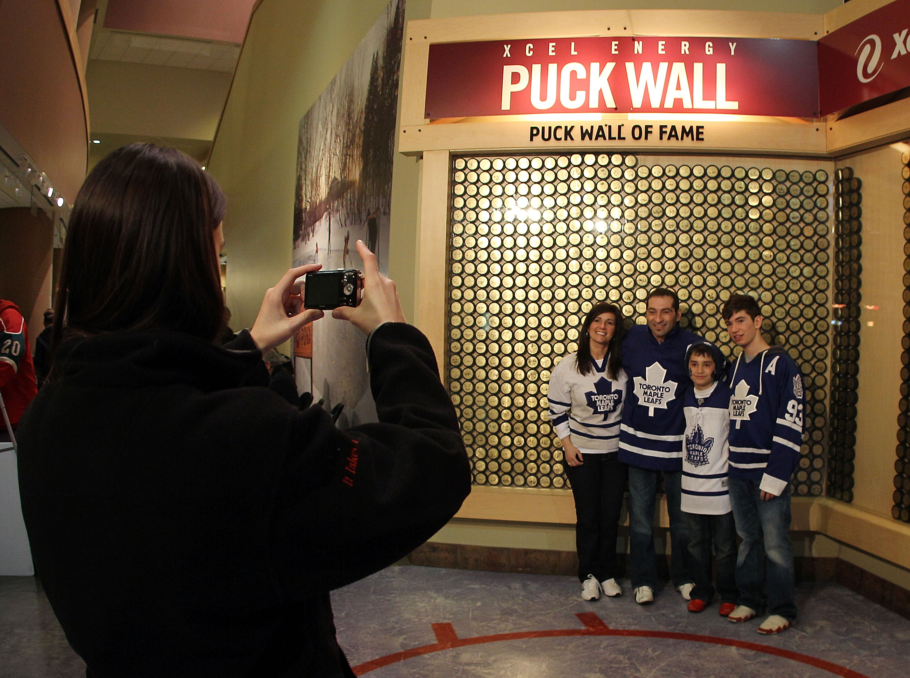 ST PAUL, MN - MARCH 22: Fans pose in front of the puck wall of fame prior to the game between the Minnesota Wild and the Toronto Maple Leafs at the Xcel Energy Center on March 22, 2011 in St Paul, Minnesota. (Photo by Bruce Bennett/Getty Images)