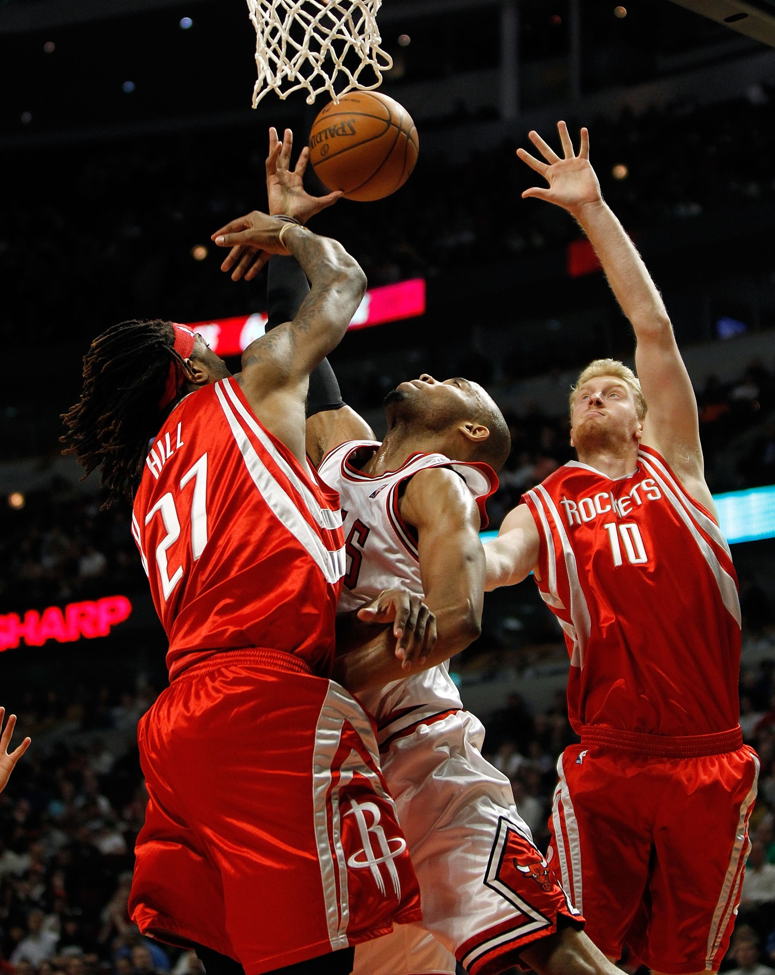 CHICAGO - MARCH 22: Taj Gibson #22 of the Chicago Bulls reaches for a rebound between Jordan Hill #27 and Chase Budinger #10 of the Houston Rockets at the United Center on March 22, 2010 in Chicago, Illinois. The Bulls defeated the Rockets 98-88. NOTE TO