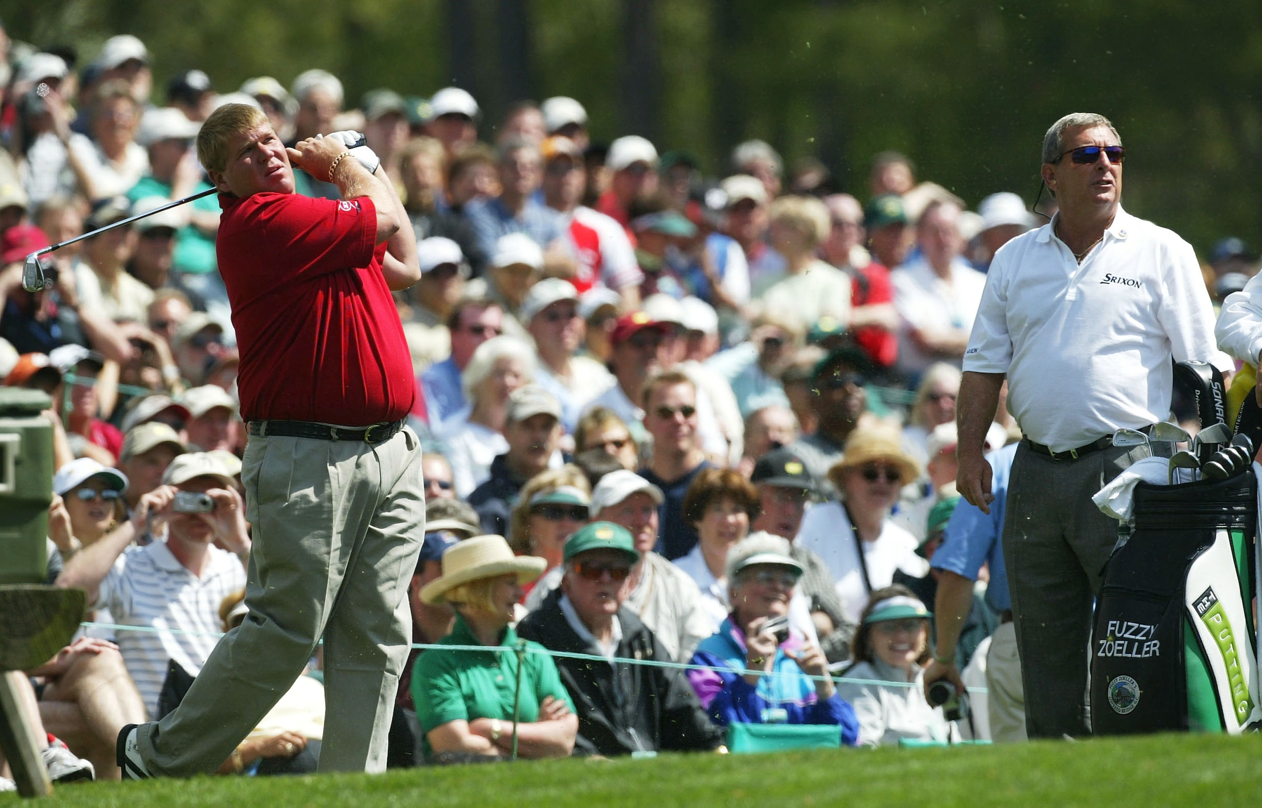 AUGUSTA, GA - APRIL 6:  John Daly of the USA hits a shot on the 12th tee as Fuzzy Zoeller looks on during the second practice day for the Masters at the Augusta National Golf Club on April 6, 2004 in Augusta, Georgia.  (Photo by David Cannon/Getty Images)