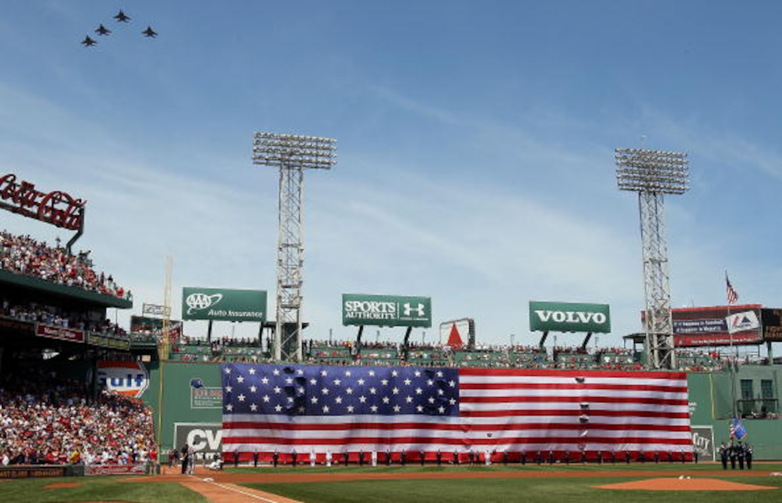 BOSTON - JULY 04:  Jets fly over as a giant flag covers the Green Monster before the game between the Baltimore Orioles and  the Boston Red Sox on July 4, 2010 at Fenway Park in Boston, Massachusetts.  (Photo by Elsa/Getty Images)