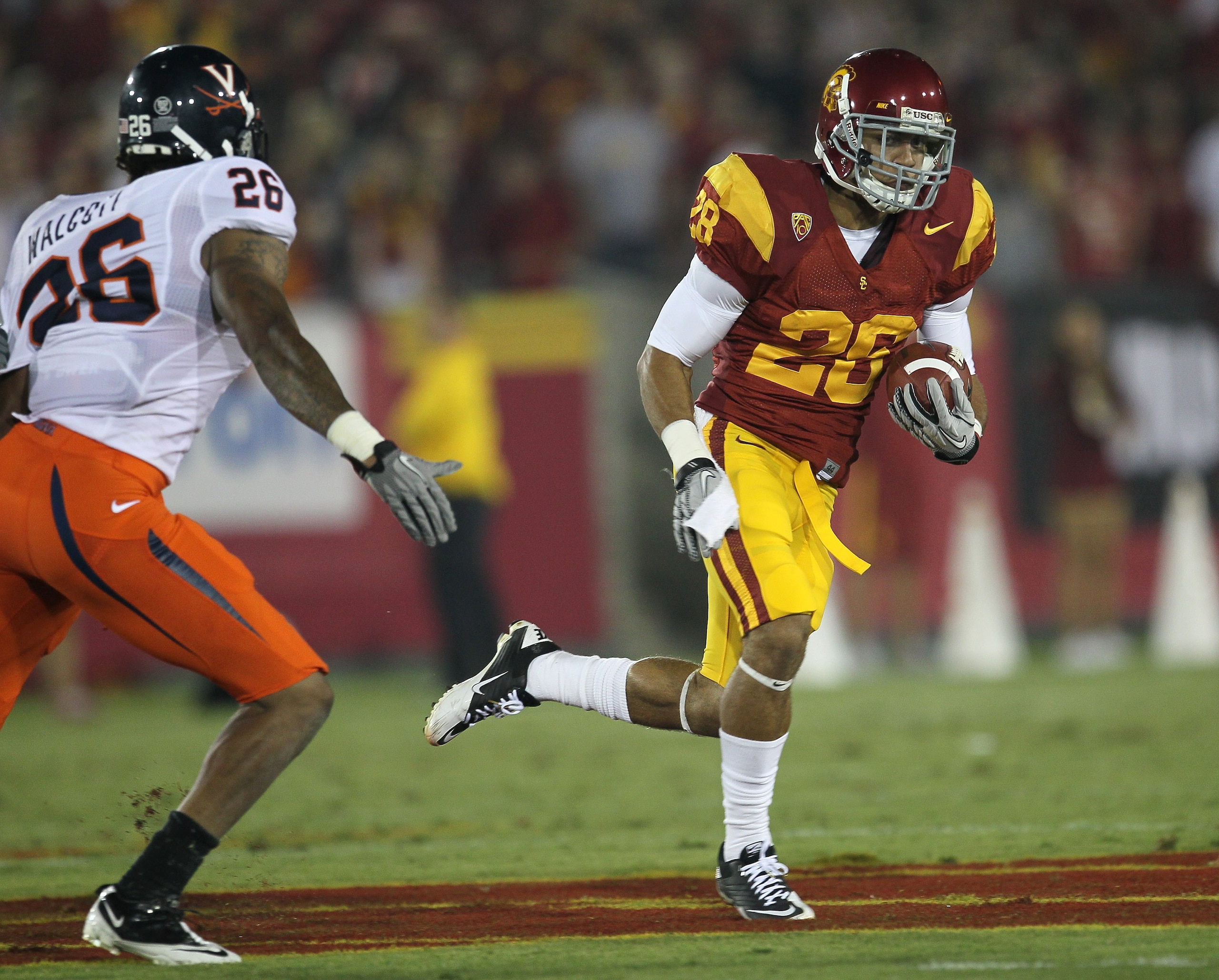 LOS ANGELES, CA - SEPTEMBER 11:  Running back Dillon Baxter #28 of the USC Trojans carries the ball against linebacker Ausar Walcott #26 of the Virginia Cavaliers at Los Angeles Memorial Coliseum on September 11, 2010 in Los Angeles, California.  (Photo b
