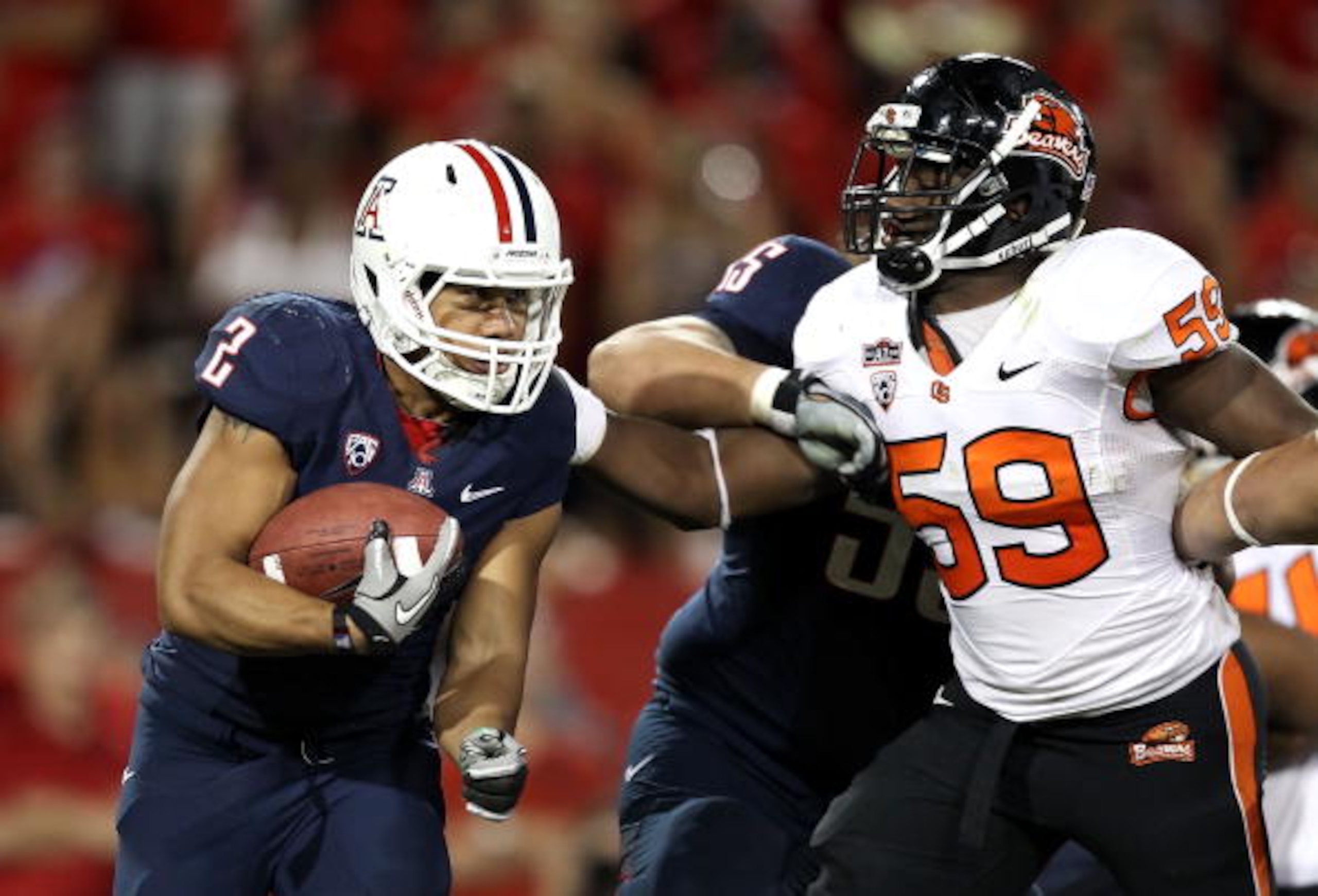 TUCSON, AZ - OCTOBER 09:  Runningback Keola Antolin #2 of the Arizona Wildcats rushes the football against Dwight Roberson #59 of the Oregon State Beavers during the college football game at Arizona Stadium on October 9, 2010 in Tucson, Arizona.  The Beav