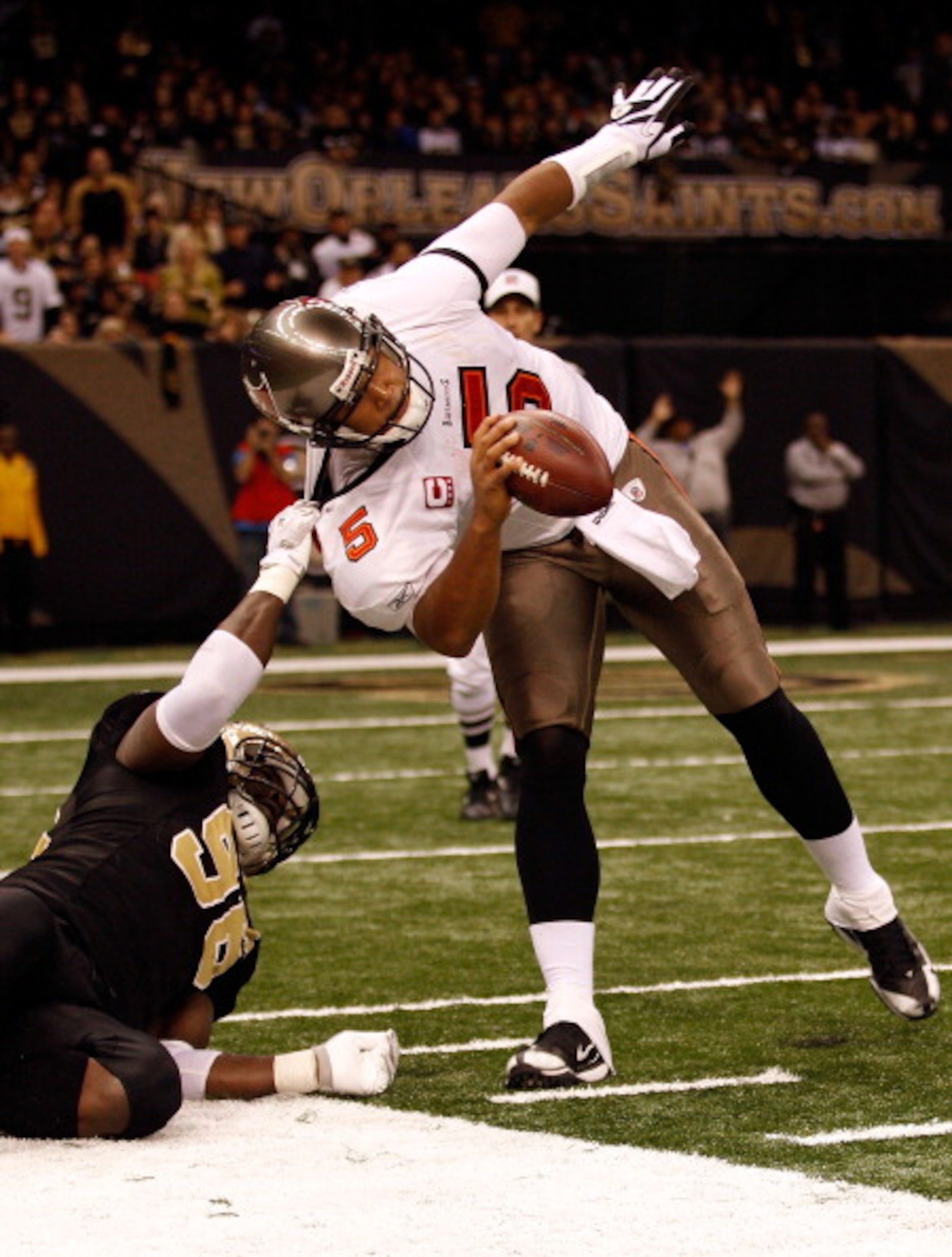 NEW ORLEANS, LA - JANUARY 02:  Quarterback Josh Freeman #5 of the Tampa Bay Buccaneers is pulled down by Alex Brown #96 of the New Orleans Saints at the Louisiana Superdome on January 2, 2011 in New Orleans, Louisiana.  The Buccaneers defeated the Saints 