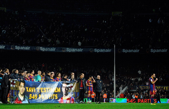 BARCELONA, SPAIN - JANUARY 02:  Xavi Hernandez of Barcelona (R)  acknowledges the crowd as his teammates holds a banner which reads 'Xavi we love you 549 games' at the end of the La Liga match between Barcelona and Levante UD at Camp Nou on January 2, 201