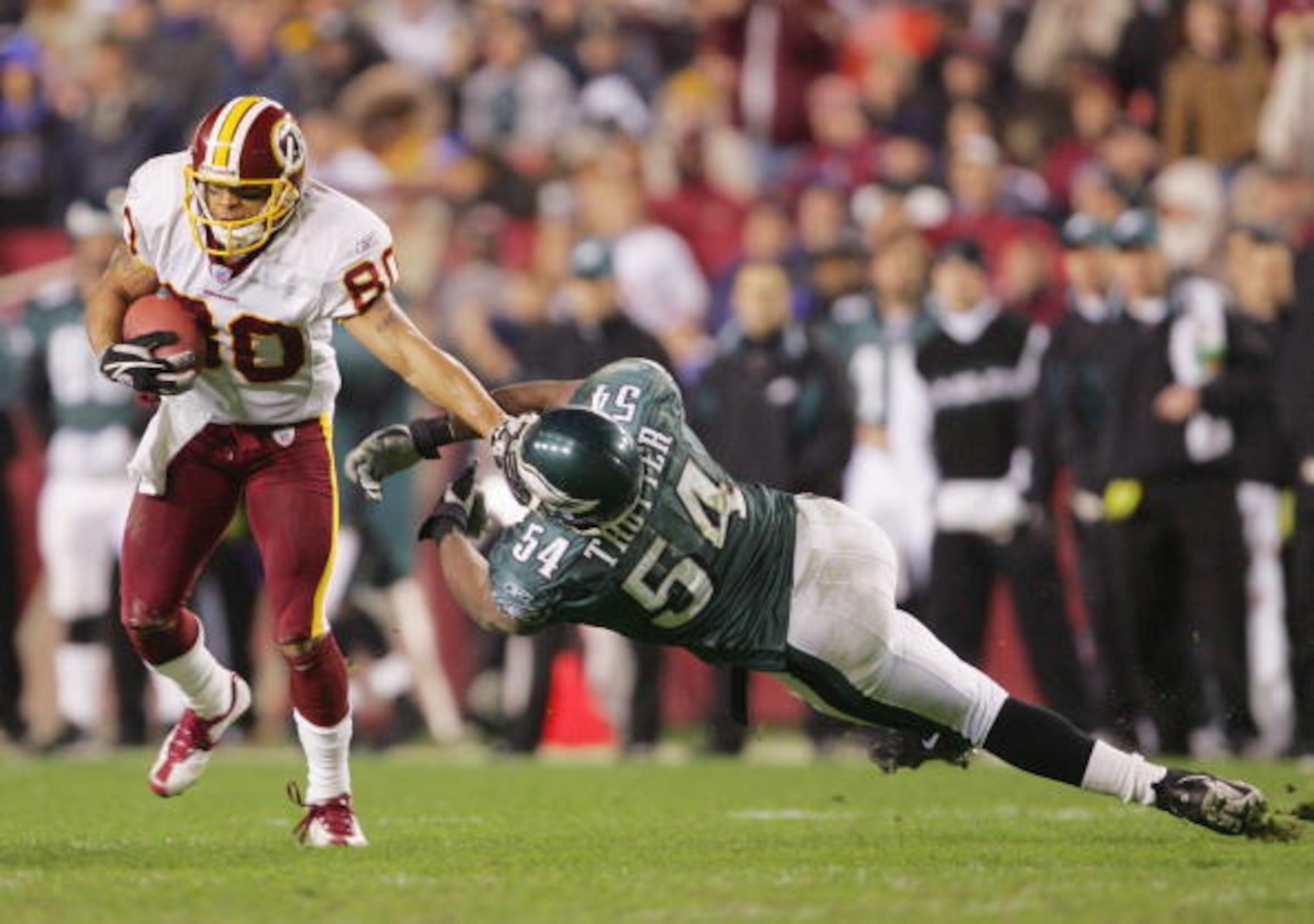 LANDOVER, MD - DECEMBER 12:  Wide receiver Laveranues Coles #80 of the Washington Redskins evades linebacker Jeremiah Trotte #54 of the Philadelphia Eagles during the game at Fed Ex Field on December 12, 2004 in Landover, Maryland.  The Eagles defeated th