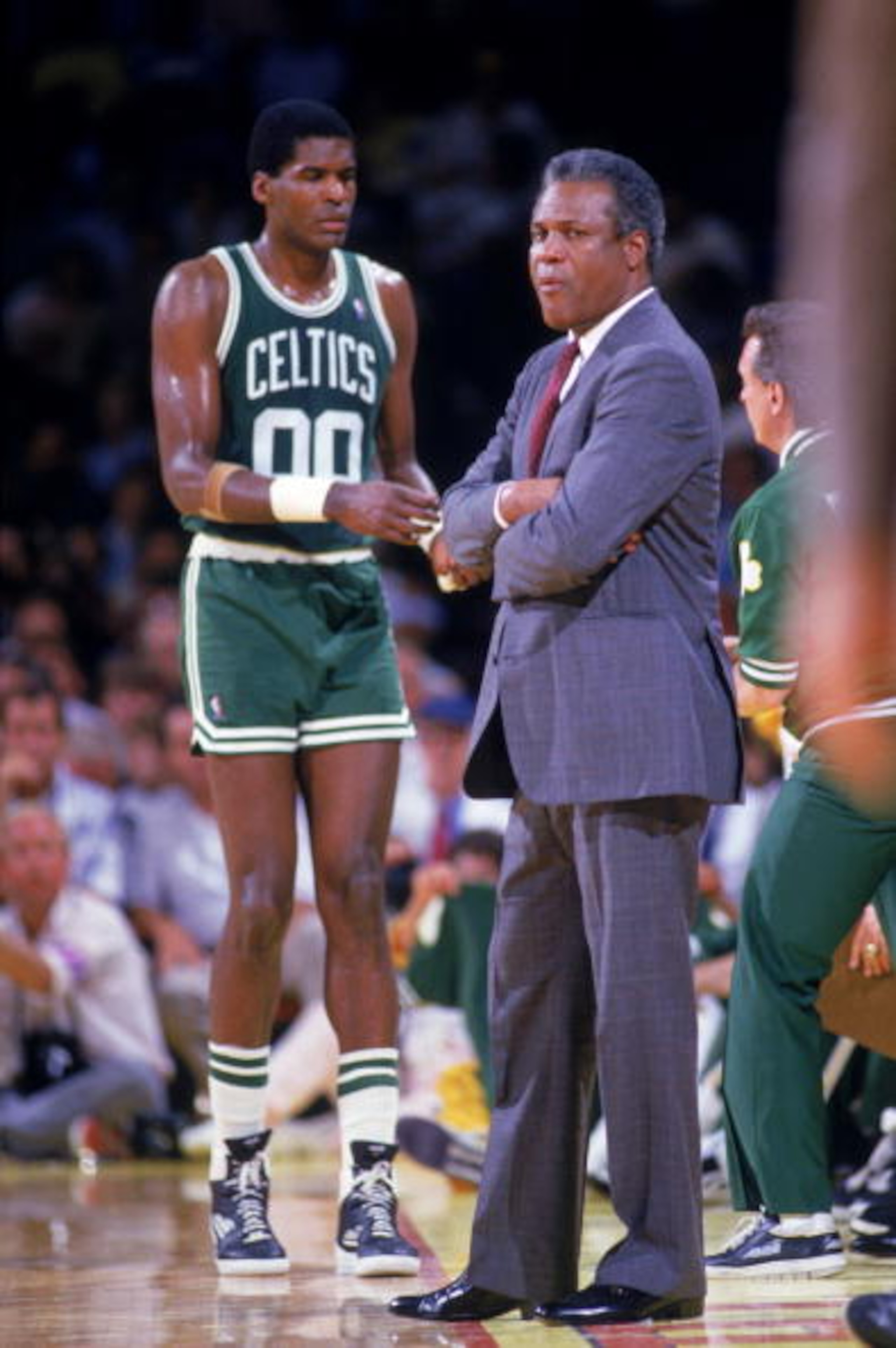 1986: Head coach K.C. Jones of the Boston Celtics looks on from the sidelines as Robert Parish #00 of the Celtics stands in the background during a game in the 1986-1987 NBA season. K.C. Jones was the head coach of the Boston Celtics from 1983-1988. (P 1986: Head coach K.C. Jones of the Boston Celtics looks on from the sidelines as Robert Parish #00 of the Celtics stands in the background during a game in the 1986-1987 NBA season. K.C. Jones was the head coach of the Boston Celtics from 1983-1988. (P