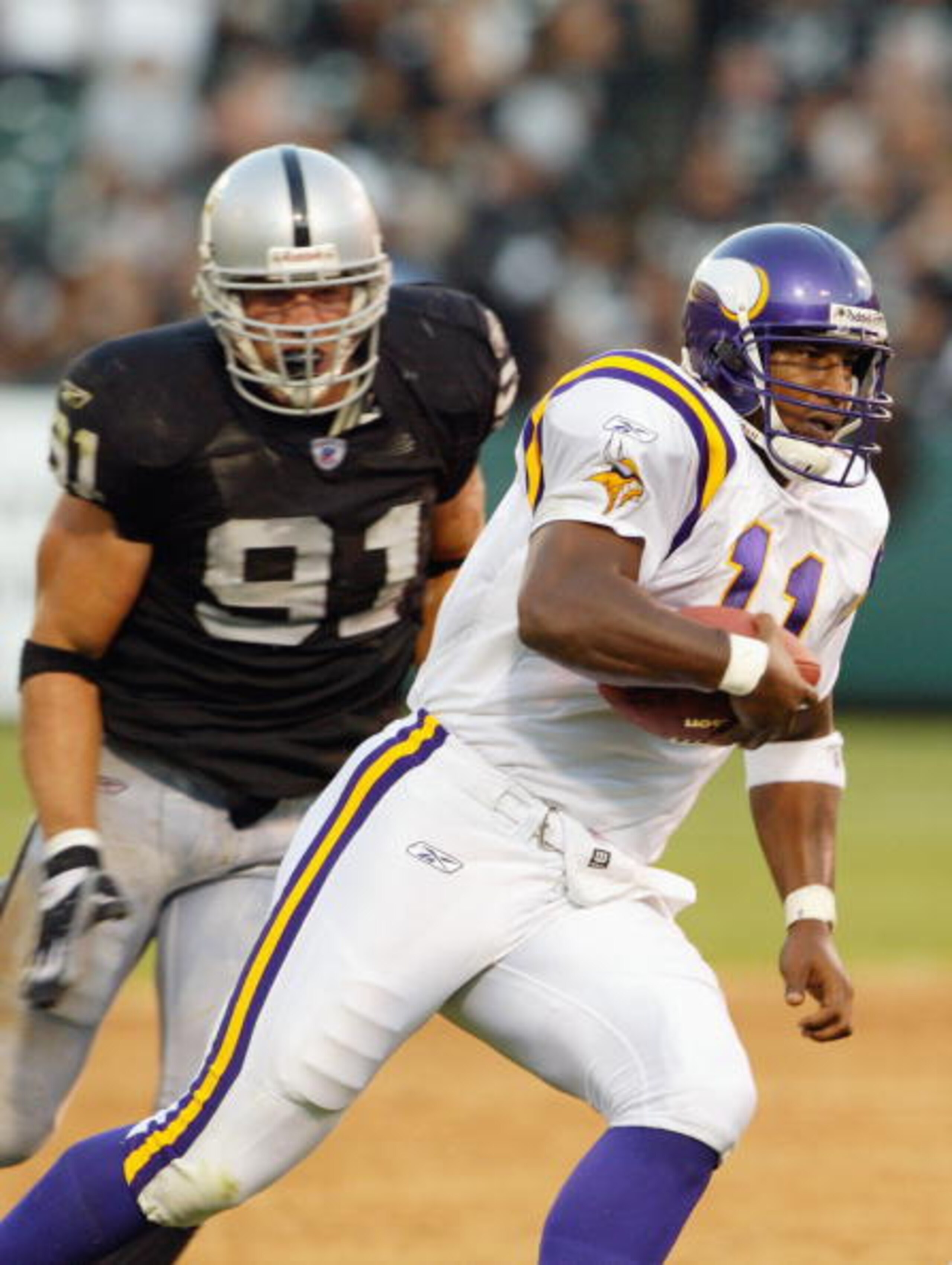 OAKLAND, CA - AUGUST 22 :  Daunte Culpepper #11 of the Minnesota Vikings scrambles as Tyler Brayton #91 of the Oakland Raiders chases him on August 22, 2003 at the Network Associates Coliseum in Oakland, California.  The Vikings defeated the Raiders 21-6.