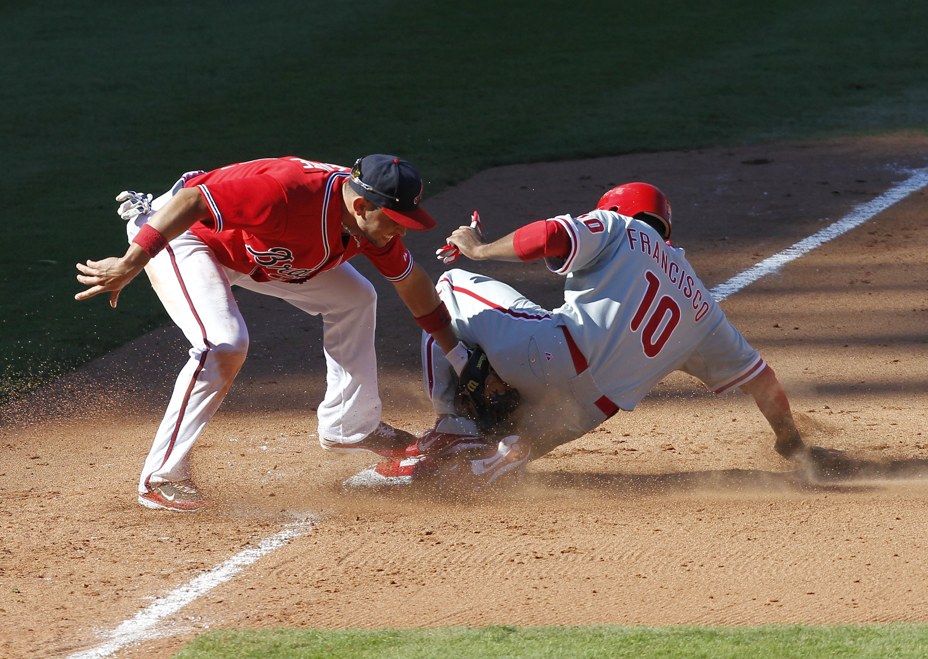 ATLANTA - OCTOBER 3:  Outfielder Ben Francisco #10 of the Philadelphia Phillies steals third base under the tag of third baseman Omar Infante #4 of the Atlanta Braves during the game at Turner Field on October 3, 2010 in Atlanta, Georgia.  (Photo by Mike