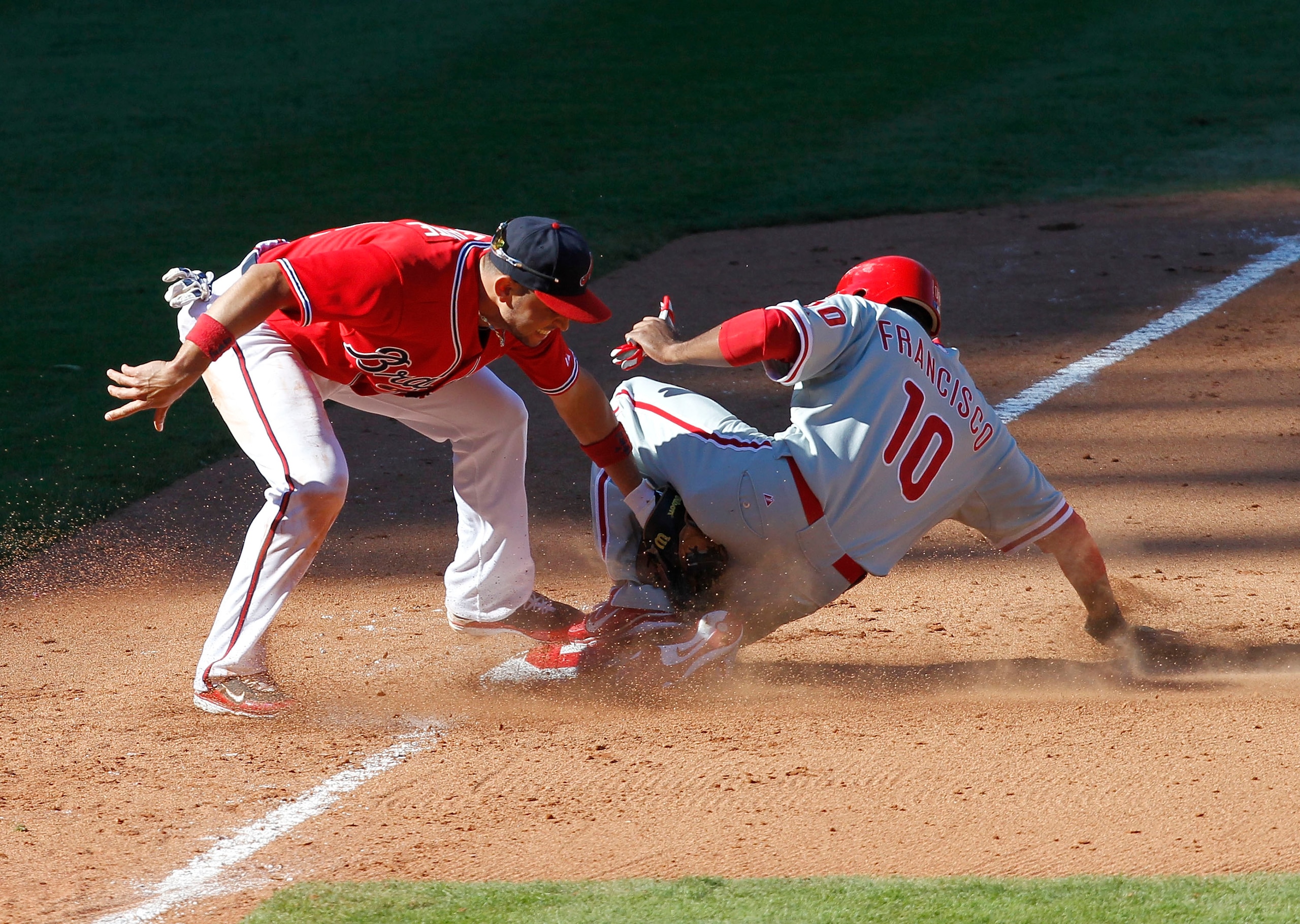ATLANTA - OCTOBER 3:  Outfielder Ben Francisco #10 of the Philadelphia Phillies steals third base under the tag of third baseman Omar Infante #4 of the Atlanta Braves during the game at Turner Field on October 3, 2010 in Atlanta, Georgia.  (Photo by Mike