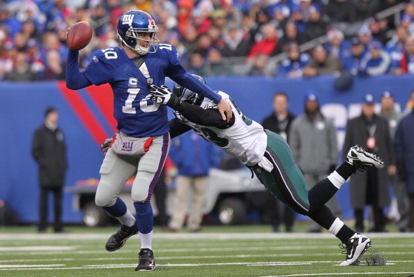 EAST RUTHERFORD, NJ - DECEMBER 19:  Eli Manning #10 of the New York Giants is sacked by Moise Fokou #53 of the Philadelphia Eagles at New Meadowlands Stadium on December 19, 2010 in East Rutherford, New Jersey.  (Photo by Nick Laham/Getty Images)
