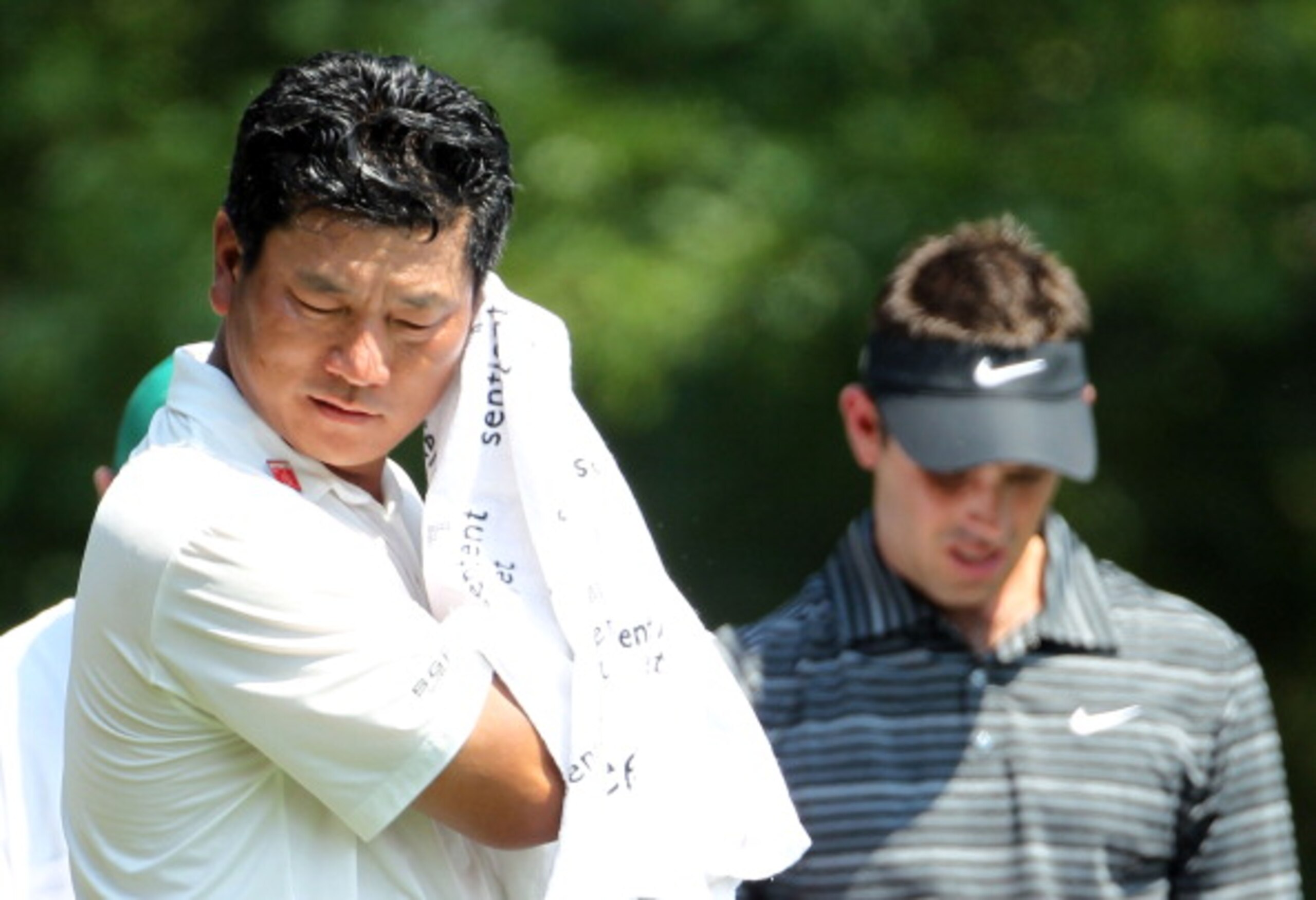 AUGUSTA, GA - APRIL 10:  K.J. Choi of South Korea wipes his face as Charl Schwartzel of South Africa looks on during the final round of the 2011 Masters Tournament at Augusta National Golf Club on April 10, 2011 in Augusta, Georgia.  (Photo by Jamie Squir