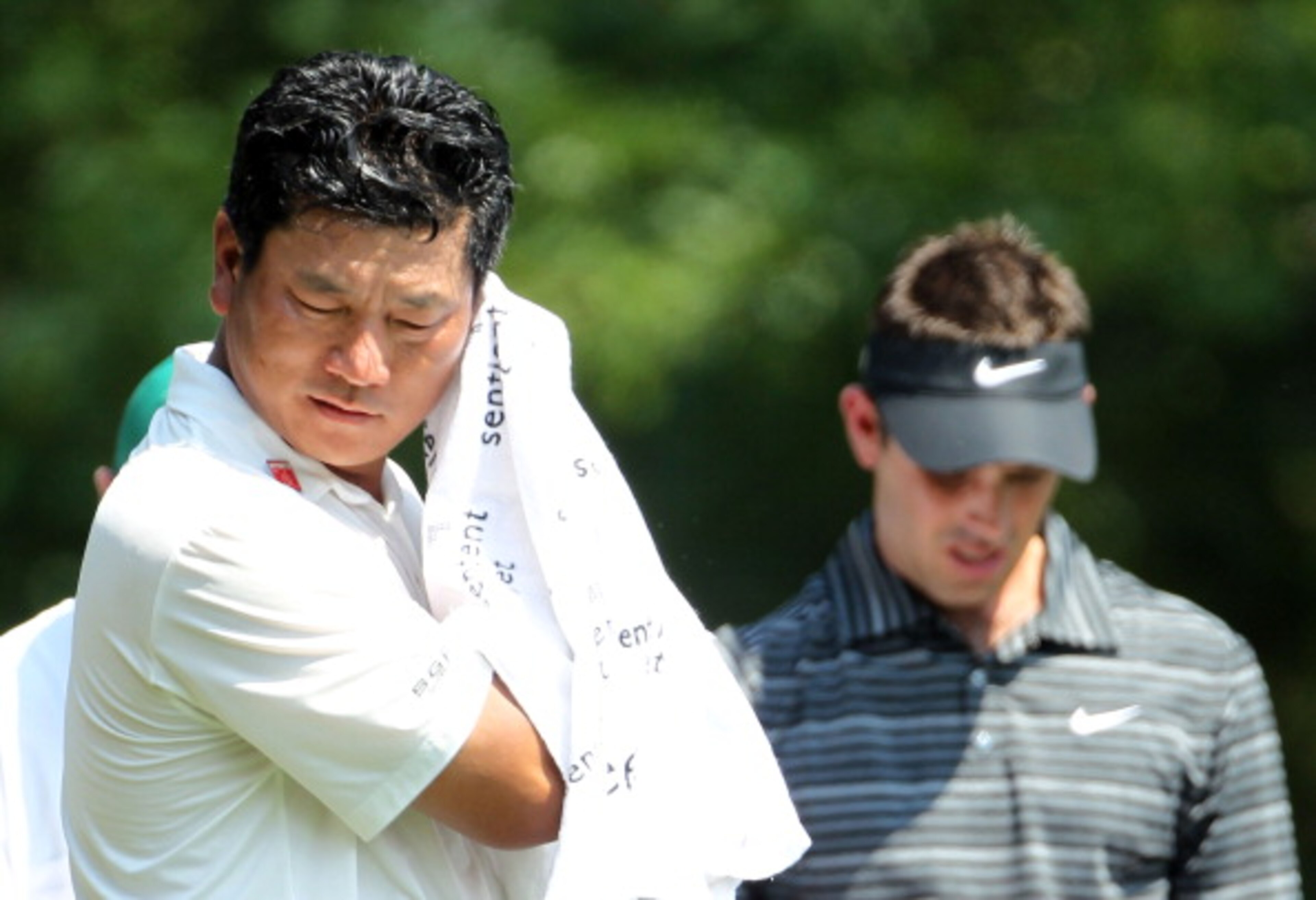 AUGUSTA, GA - APRIL 10:  K.J. Choi of South Korea wipes his face as Charl Schwartzel of South Africa looks on during the final round of the 2011 Masters Tournament at Augusta National Golf Club on April 10, 2011 in Augusta, Georgia.  (Photo by Jamie Squir