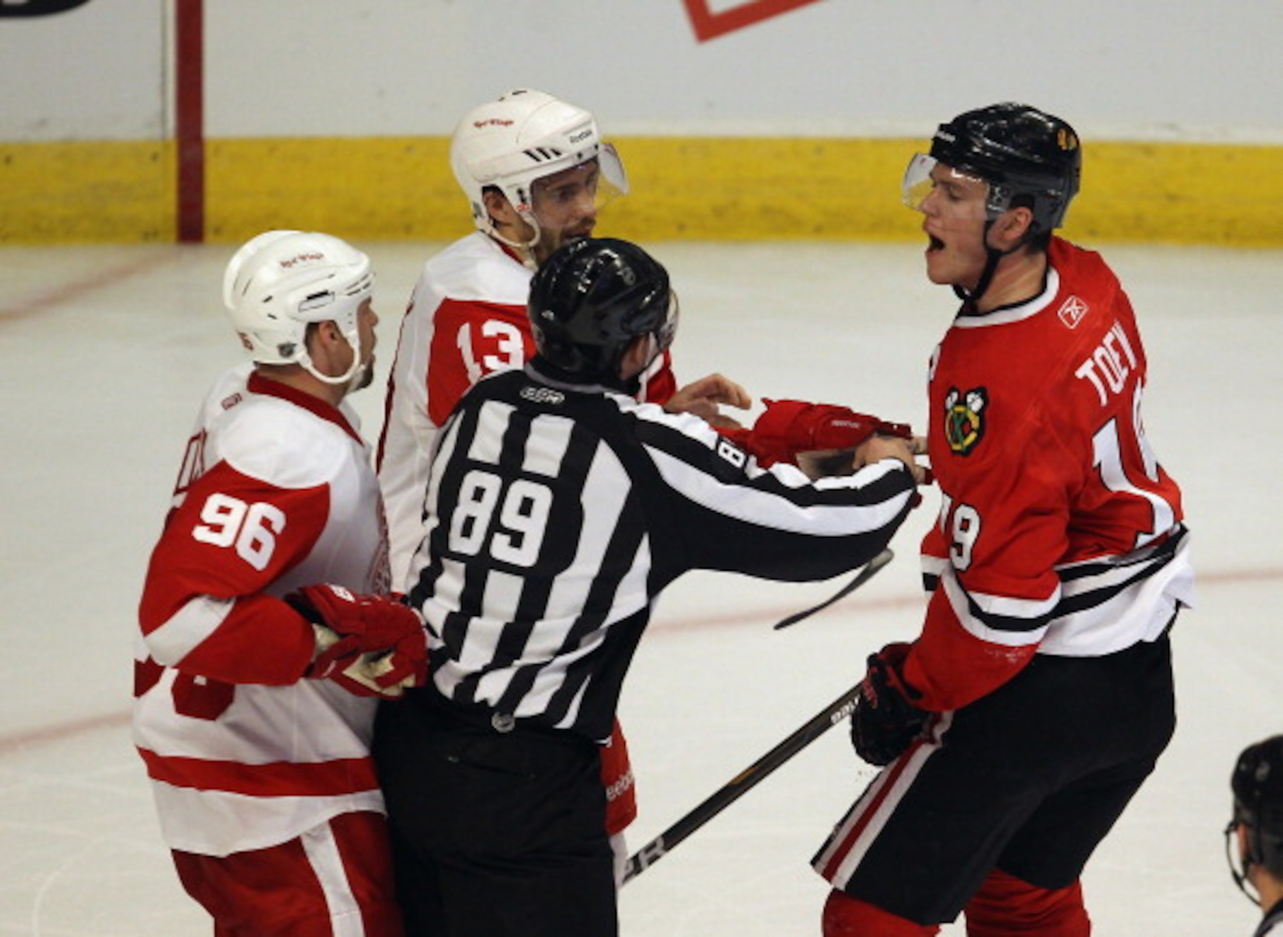 CHICAGO, IL - APRIL 10: Jonathan Toews #19 of the Chicago Blackhawks has words with Tomas Holmstrom #96 and Pavel Datsyuk #13 of the Detroit Red Wings as linesman Steve Miller #89 stands between them at the United Center on April 10, 2011 in Chicago, Illi