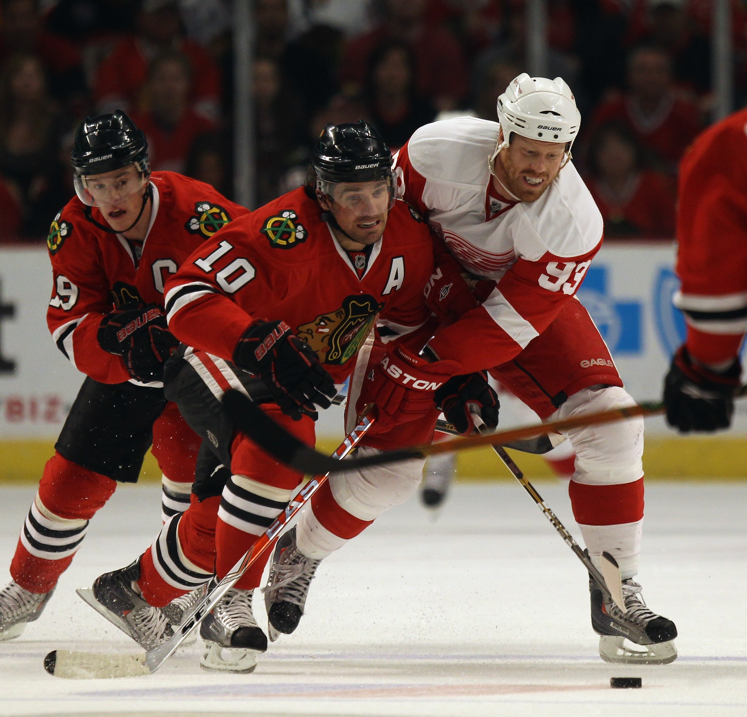 CHICAGO, IL - APRIL 10: Patrick Sharp #10 of the Chicago Blackhawks battles for the puck with Johan Franzen #93 of the Detroit Red Wings as Jonathan Toews #19 trails the play at the United Center on April 10, 2011 in Chicago, Illinois. The Red Wings defea