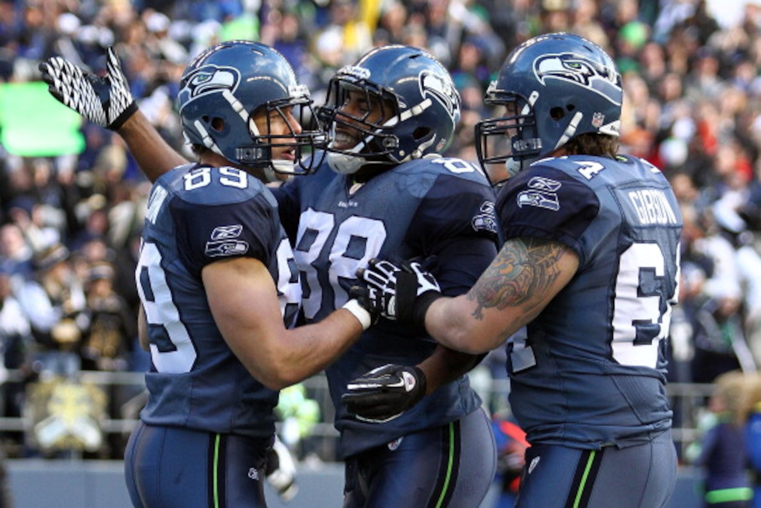 SEATTLE, WA - JANUARY 08:  John Carlson #89 of the Seattle Seahawks celebrates his 11-yard first quarter touchdown reception with teammates Cameron Morrah #88 and Mike Gibson #64 against the New Orleans Saints during the 2011 NFC wild-card playoff game at