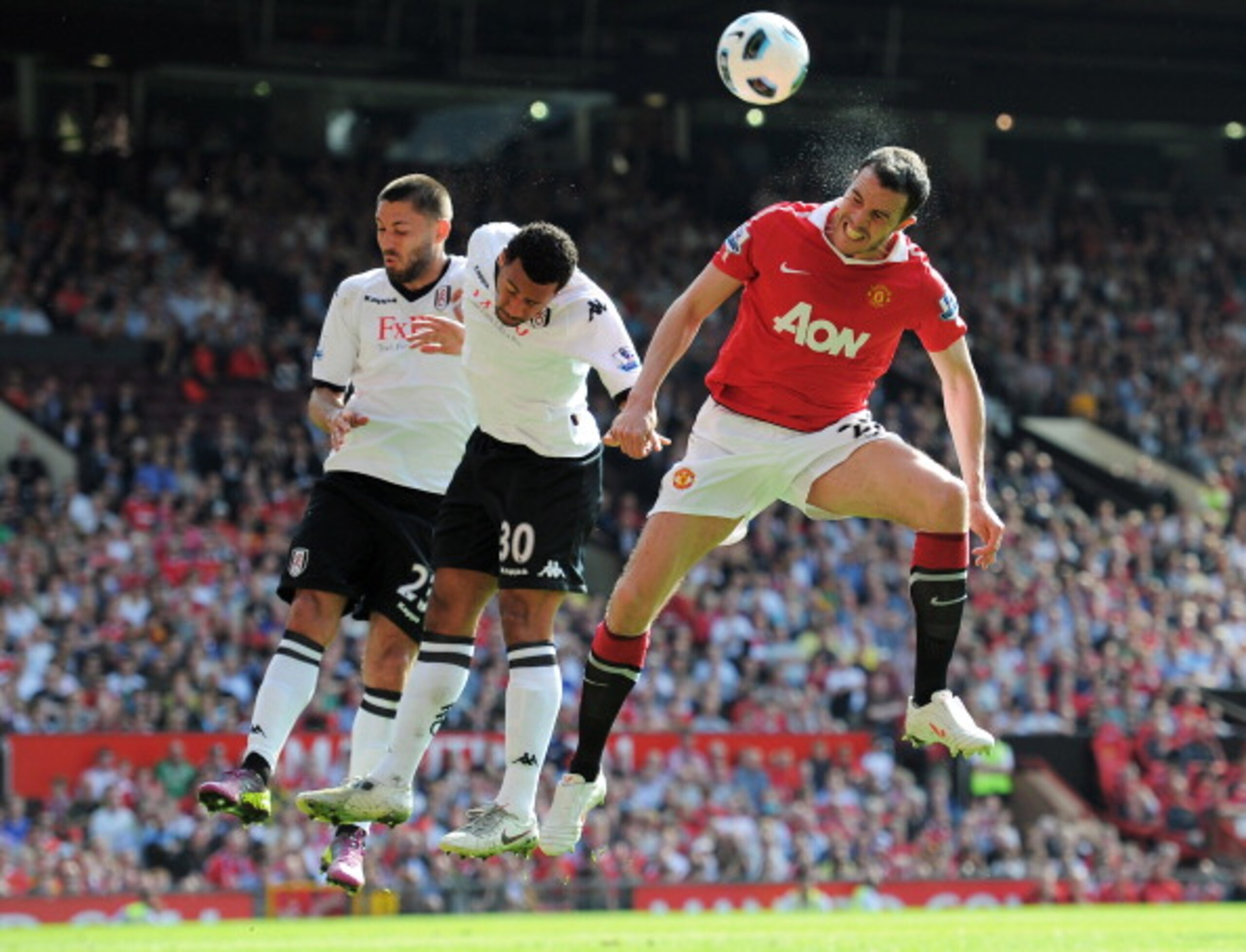 MANCHESTER, ENGLAND - APRIL 09: John O'Shea of Manchester United wins a header against Moussa Dembele and Clint Dempsey (L) of Fulham during the Barclays Premier League match between Manchester United and Fulham at Old Trafford on April 9, 2011 in Manches