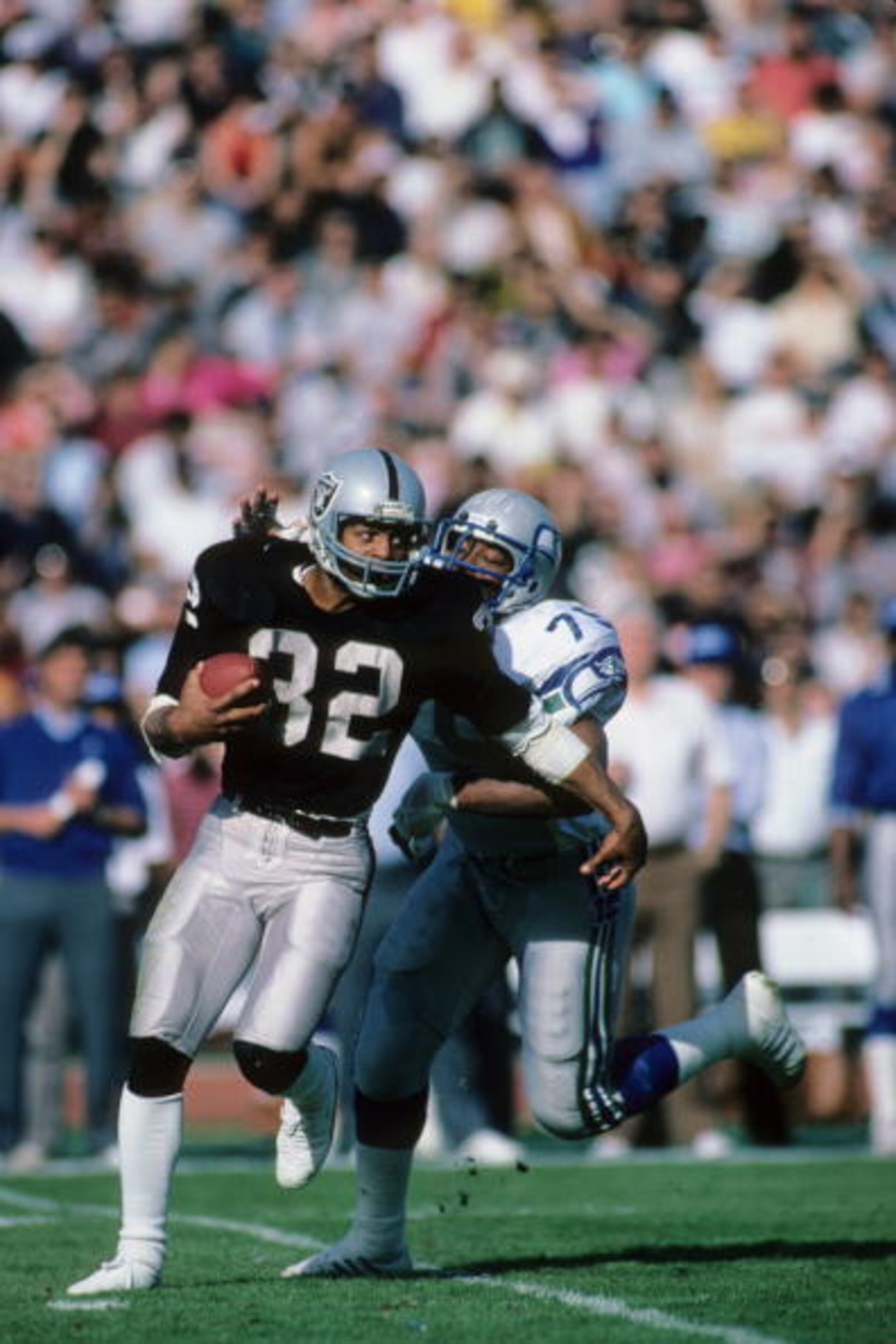 LOS ANGELES, CA - DECEMBER 15:  Marcus Allen #32 of the Los Angeles Raiders is grabbed from behind by Jacob Green #79 of the Seattle Seahawks during the game at the Los Angeles Memorial Coliseum on December 15, 1985 in Los Angeles, California.  The Raider