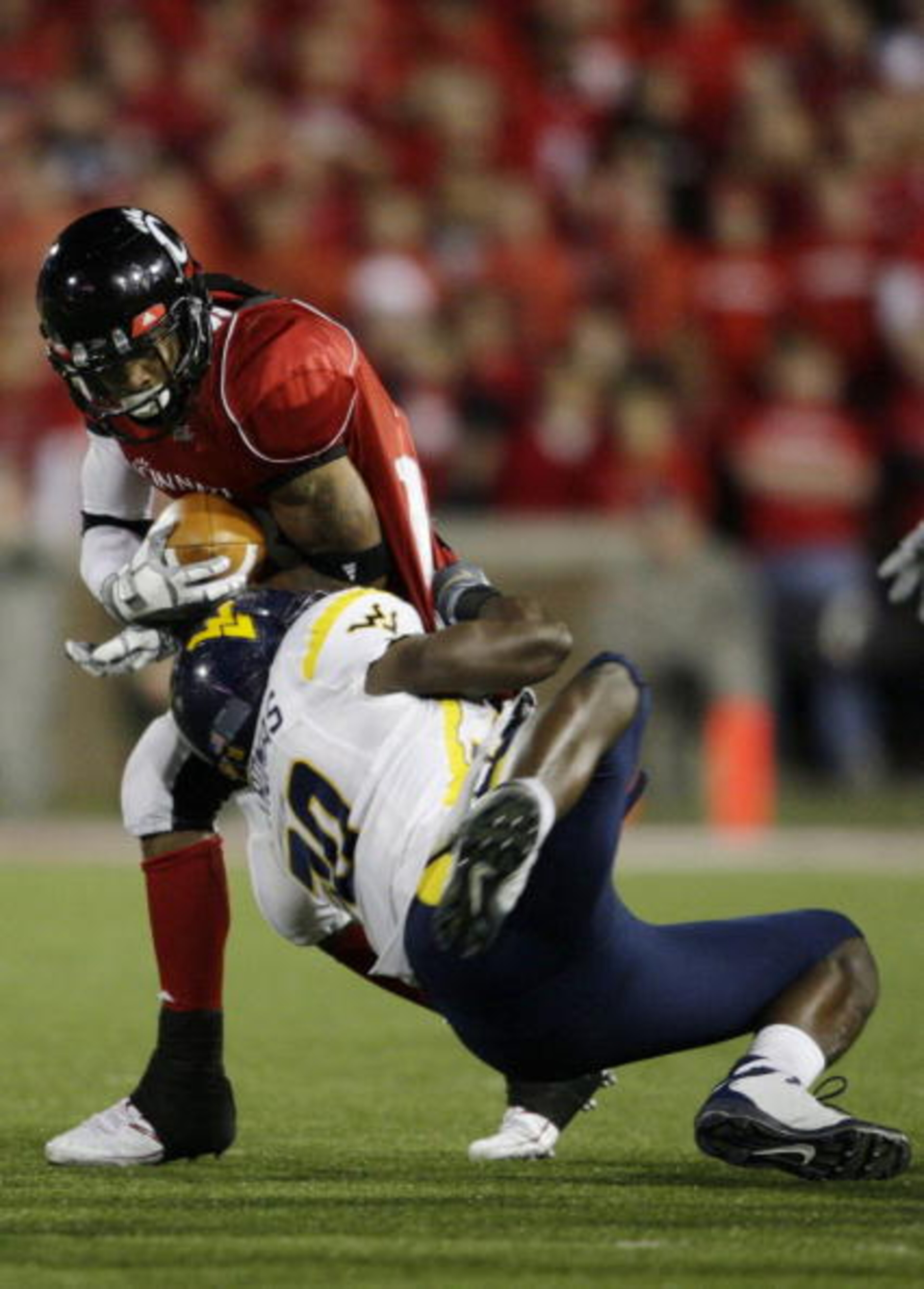 CINCINNATI - NOVEMBER 13: Isaiah Pead #23 of the Cincinnati Bearcats is tackled by J.T. Thomas #30 of the West Virginia Mountaineers during the third quarter of the game at Nippert Stadium on November 13, 2009 in Cincinnati, Ohio.  (Photo by Andy Lyons/Ge