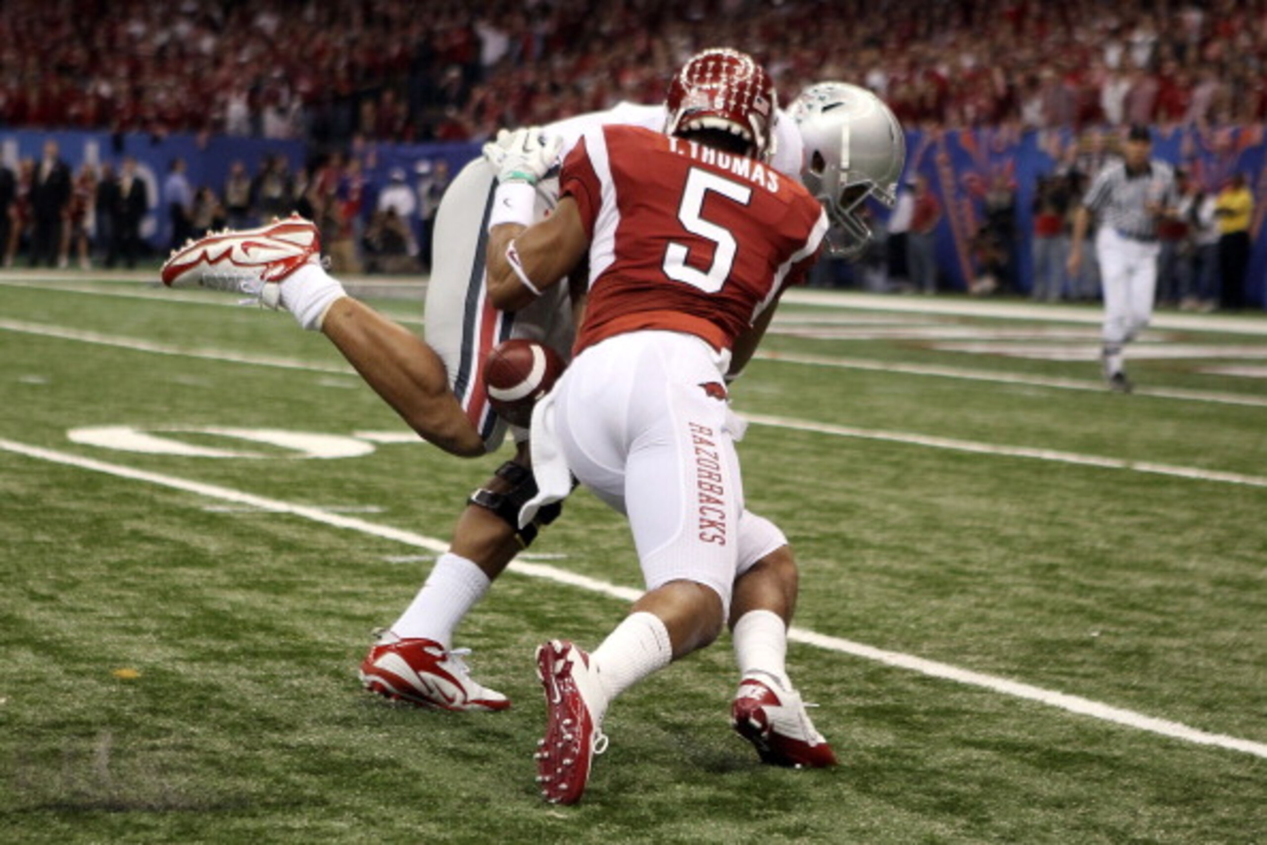 NEW ORLEANS, LA - JANUARY 04:  Terrelle Pryor #2 of the Ohio State Buckeyes fumbles the football alongside Isaac Madison #6 of the Arkansas Razorbacks in the first quarter against the Arkansas Razorbacks during the Allstate Sugar Bowl at the Louisiana Sup