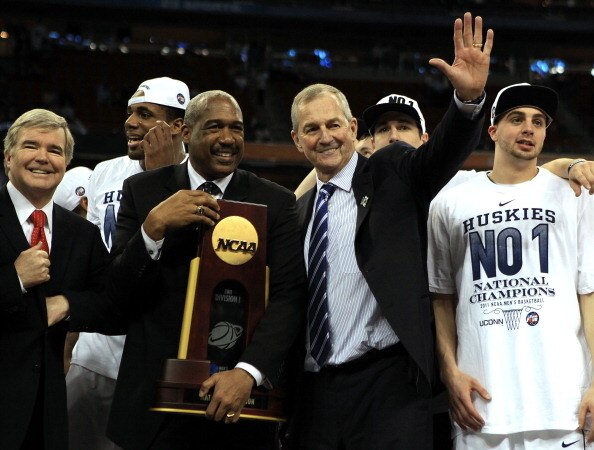 HOUSTON, TX - APRIL 04:  Athletic director Gene Smith of the Ohio State Buckeyes stands with head coach Jim Calhoun of the Connecticut Huskies as the Huskies celebrate with his team and the trophy after defeating the Butler Bulldogs to win the National Ch