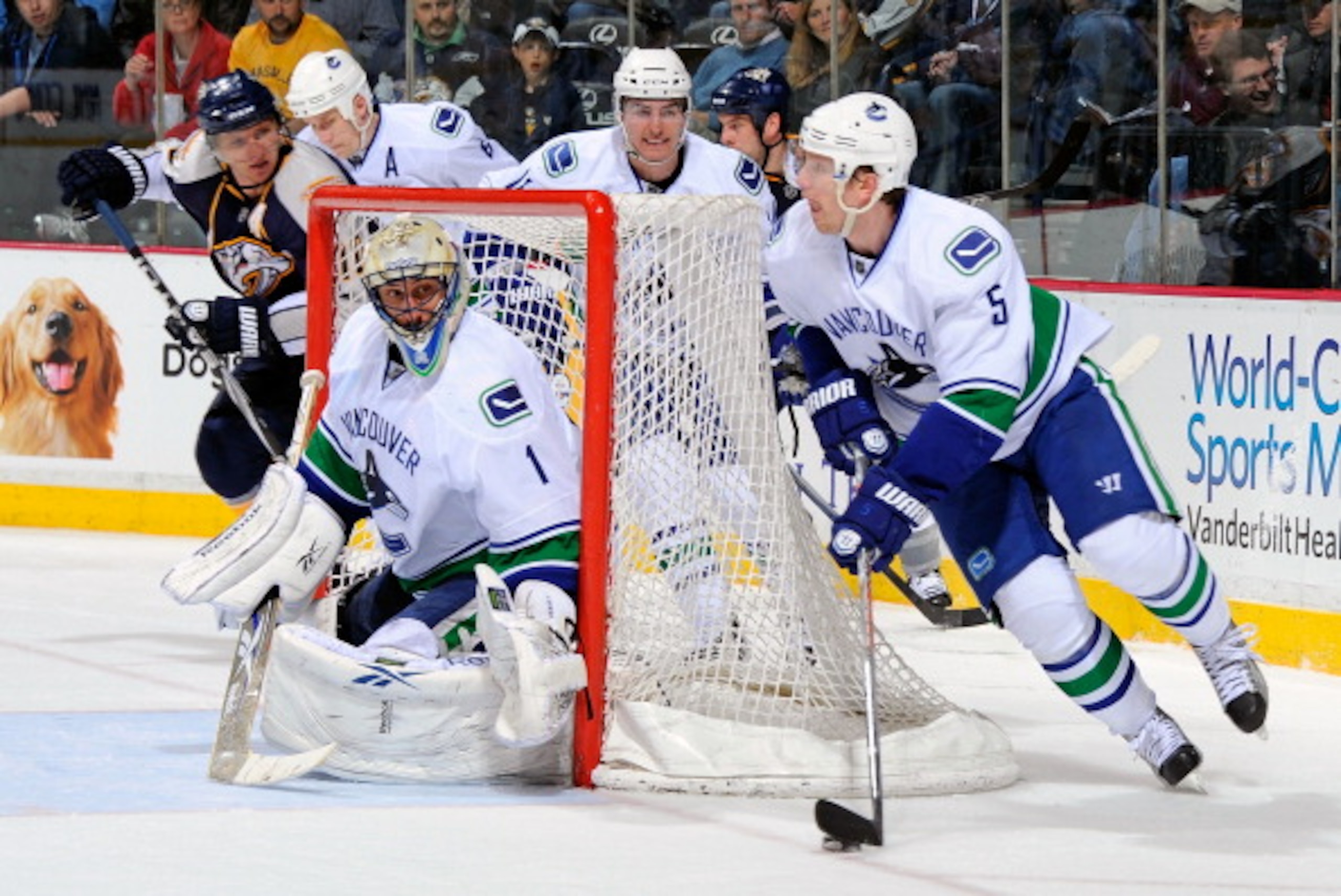 NASHVILLE, TN - MARCH 29:  Christian Ehrhoff #5 of the Vancouver Canucks carries the puck behind teammate Roberto Luongo and away from Martin Erat #10 the Nashville Predators on March 29, 2011 at the Bridgestone Arena in Nashville, Tennessee.  (Photo by F