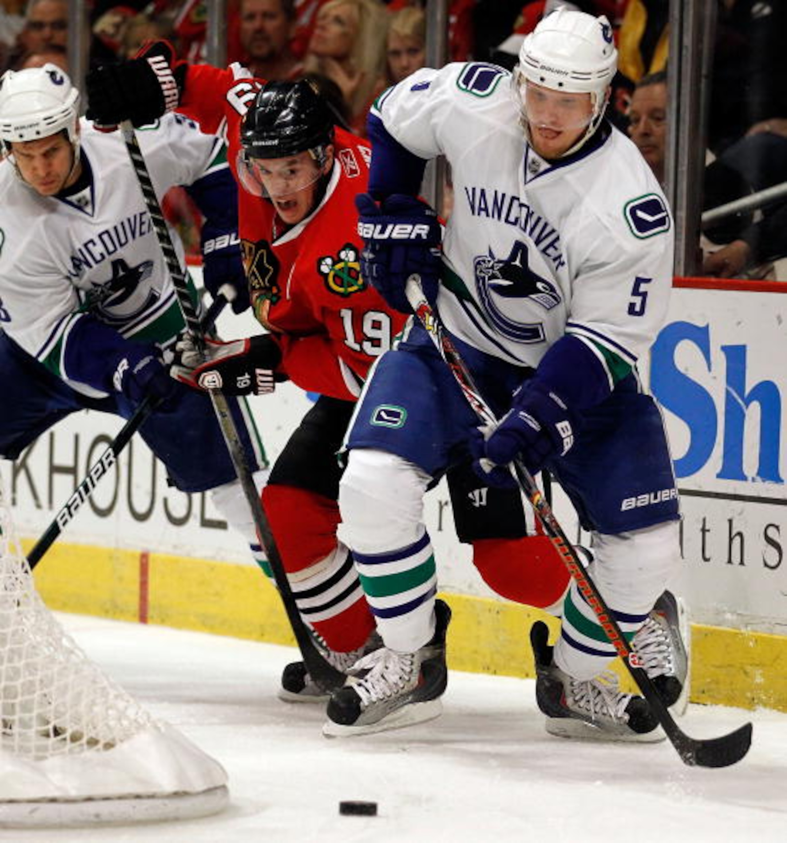 CHICAGO - MAY 09: Jonathan Toews #19 of the Chicago Blackhawks slips between Kevin Bieksa #3 and Christian Ehrhoff #5 of the Vancouver Canucks as they move to the puck in Game Five of the Western Conference Semifinals during the 2010 NHL Stanley Cup Playo