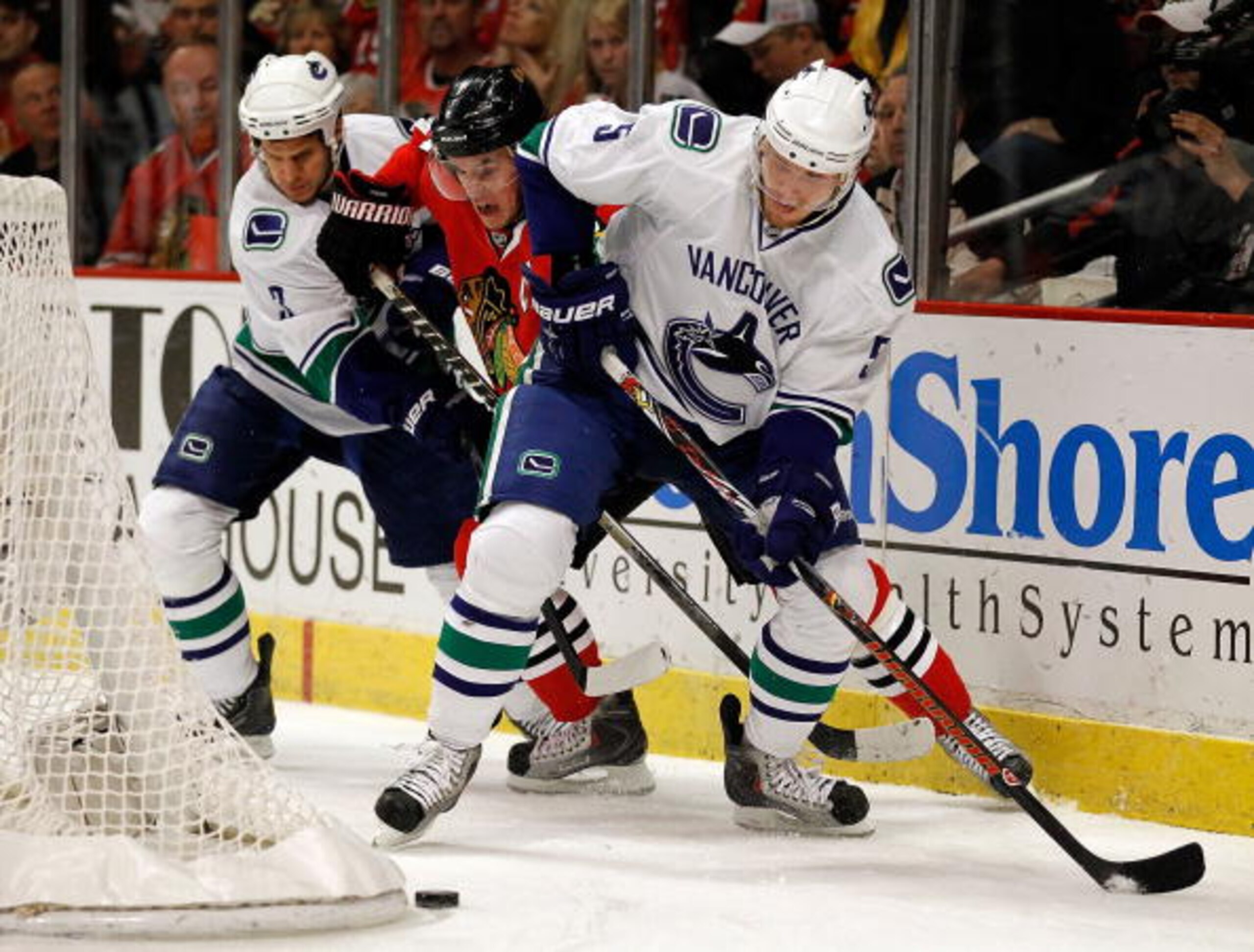CHICAGO - MAY 09: Jonathan Toews #19 of the Chicago Blackhawks tries to slip between Kevin Bieksa #3 and Christian Ehrhoff #5 of the Vancouver Canucks as they move to the puck in Game Five of the Western Conference Semifinals during the 2010 NHL Stanley C