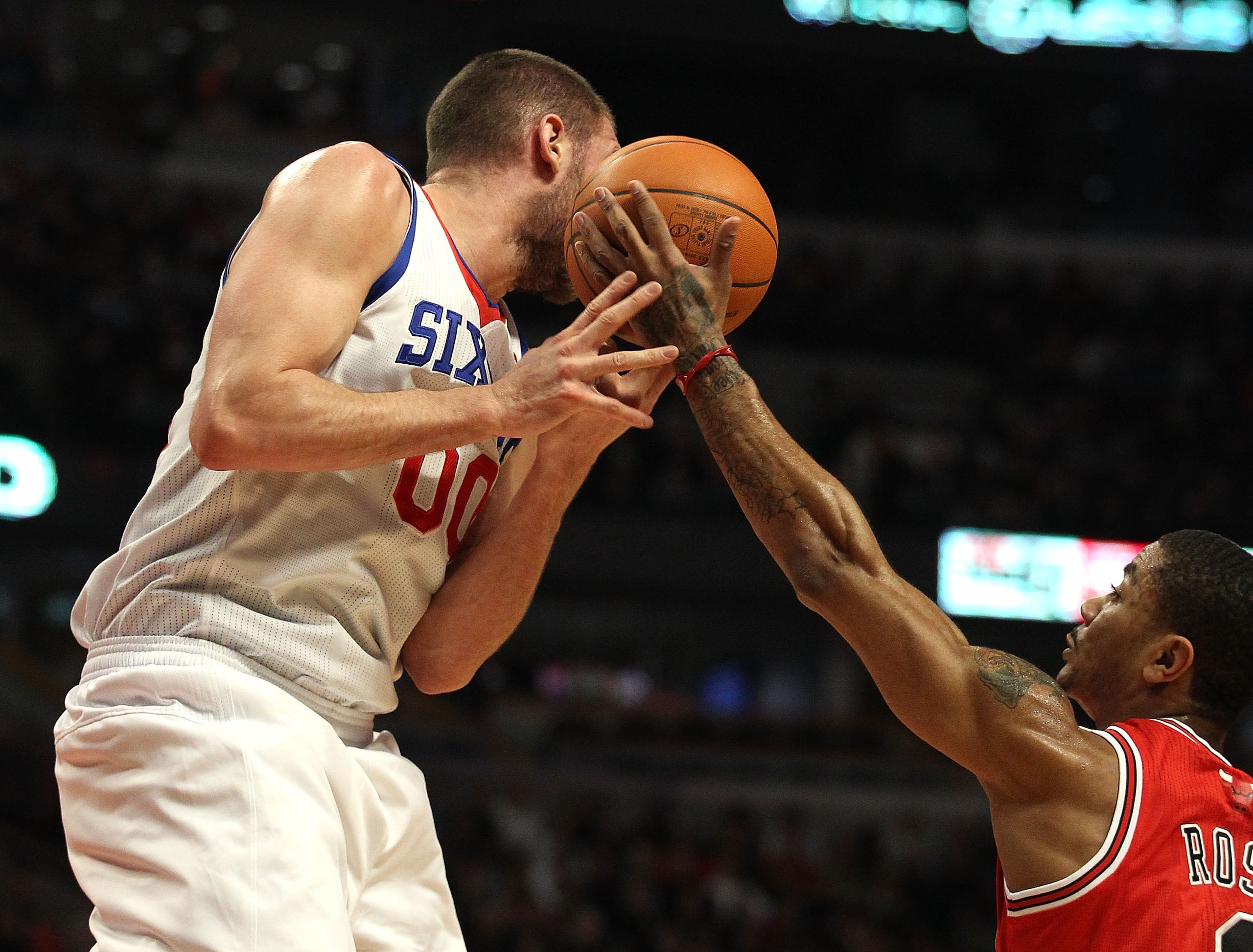 CHICAGO, IL - MARCH 28: Derrick Rose #1 of the Chicago Bulls reaches for the ball going off of the face of Spencer Hawes #00 of the Philadelphia 76ers at the United Center on March 28, 2011 in Chicago, Illinois. NOTE TO USER: User expressly acknowledges a