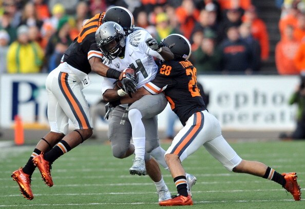 CORVALLIS, OR - DECEMBER 4: Kenjon Barner #24 of the Oregon Ducks struggles for some extra yards as Lance Mitchell #10 and Suaesi Tuimaunei #28 of the Oregon State Beavers in the second quarter of the game at Reser Stadium on December 4, 2010 in Corvallis