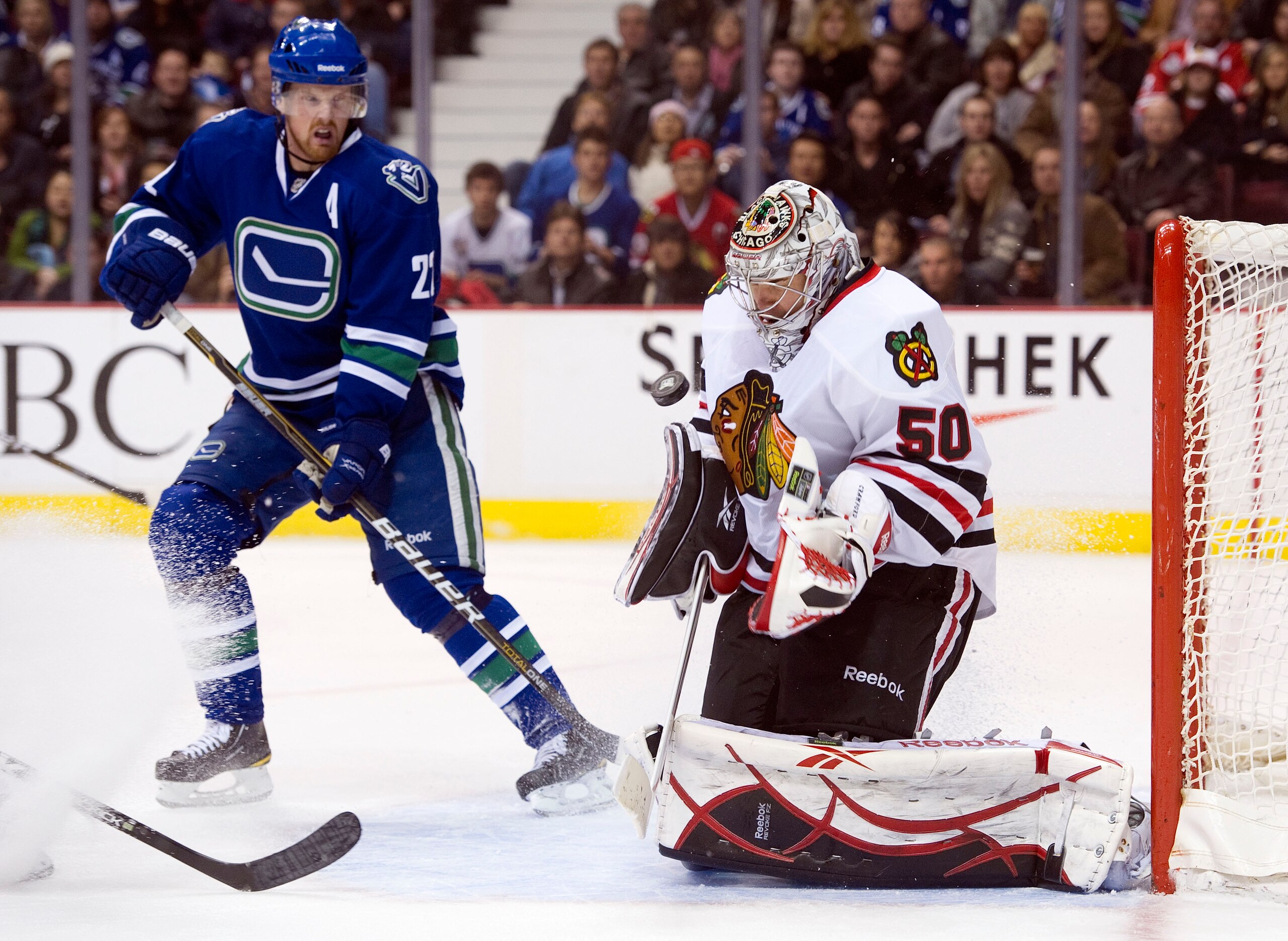 VANCOUVER, CANADA - NOVEMBER 20: Goalie Corey Crawford #50 of the Chicago Blackhawks makes a save while Daniel Sedin #22 looks for a rebound during the second period in NHL action on November 20, 2010 at Rogers Arena in Vancouver, British Columbia, Canada