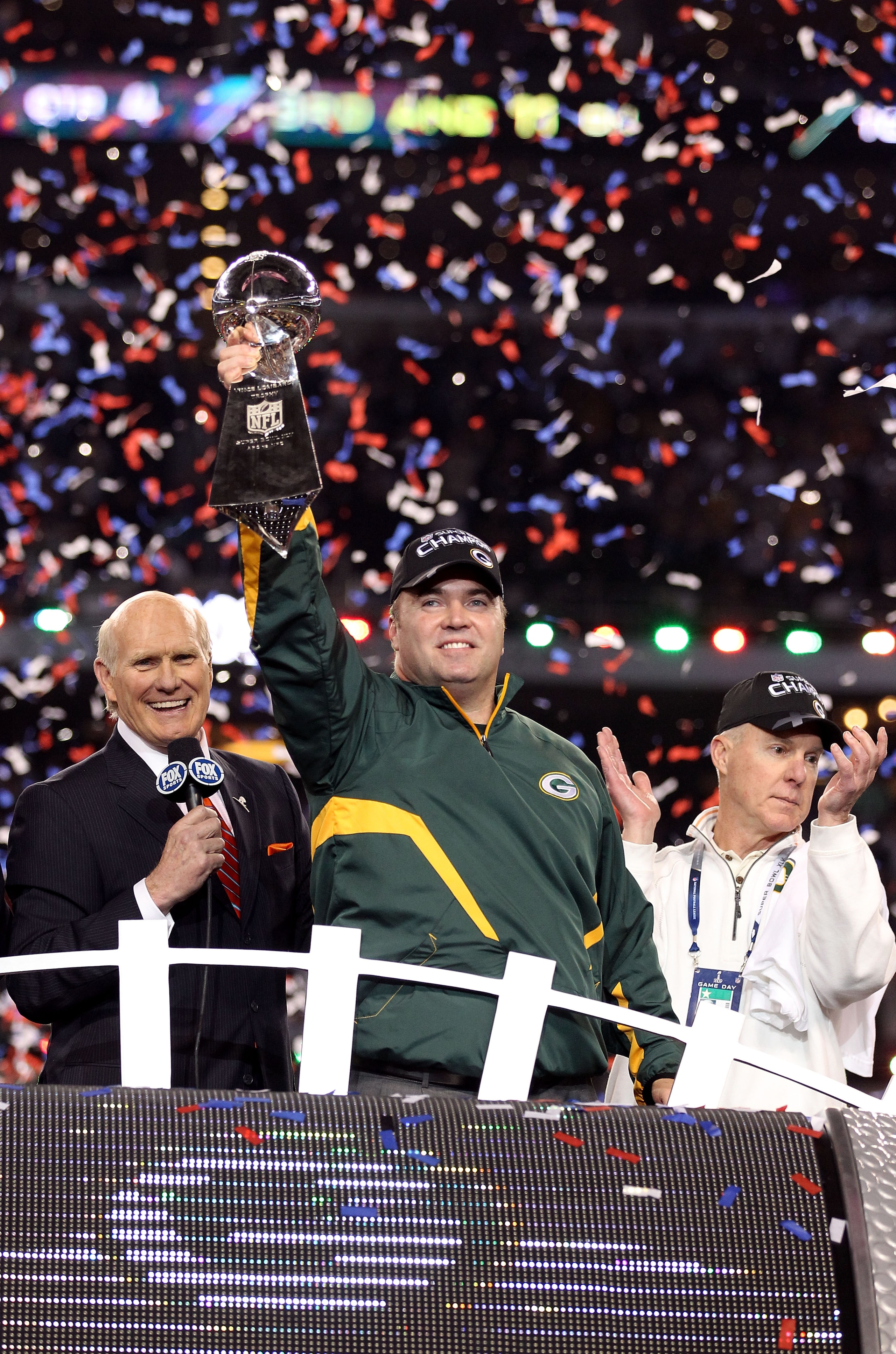 ARLINGTON, TX - FEBRUARY 06:  Head coach Mike McCarthy of the Green Bay Packers celebrates with the Vince Lombardi trophy as FOX analyast Terry Bradshaw and Packers' General manager Ted Thompson looks on following the Packers 31-25 win in Super Bowl XLV a